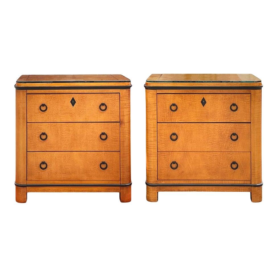 A beautiful pair of Biedermeier wood nightstands by National Mt. Airy. These three-drawer nightstands feature circular brushed metal pulls and includes locking drawers with key. Ebonized detailing on top and base. These are vintage and have some