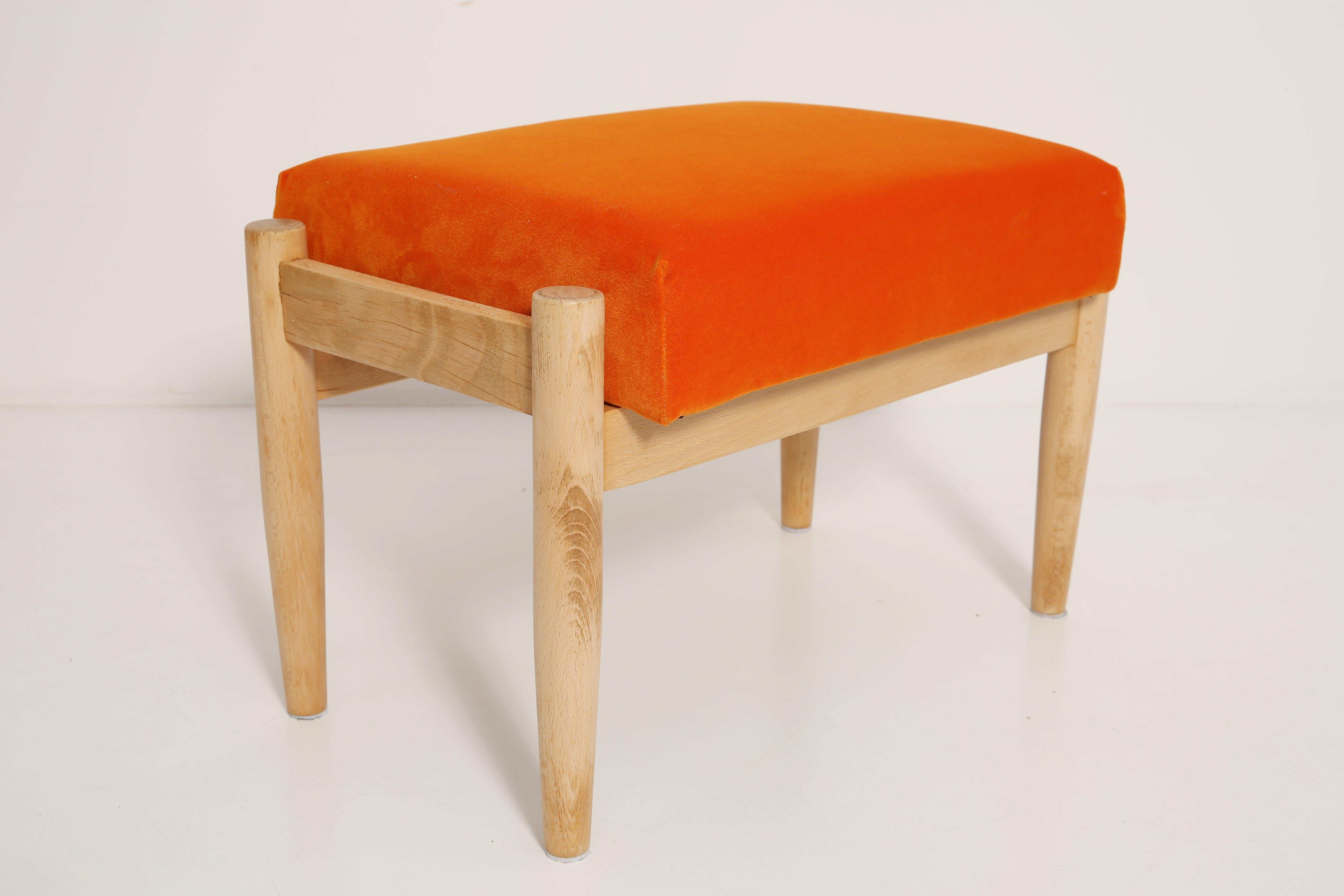 Hocker aus der Zeit um die 1960er Jahre. Schöne leuchtend orangefarbene, hochwertige Samtpolsterung. Der Hocker besteht aus einem gepolsterten Teil, einer Sitzfläche und sich nach unten verjüngenden Holzbeinen, die für den Stil der 1960er Jahre