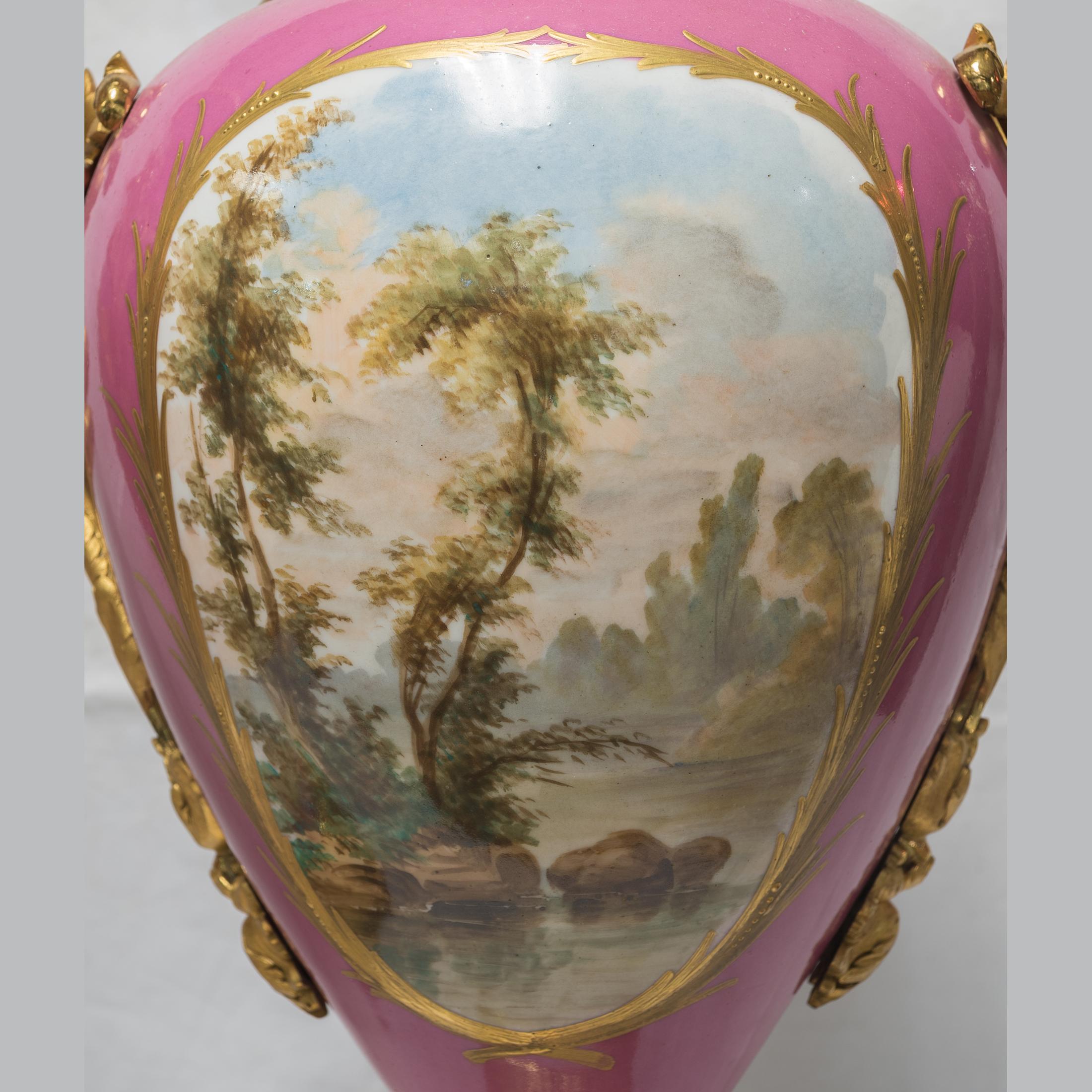 A fine quality pair of ormolu mounted Sèvres style porcelain pink-ground vases.
Each painted with courtly scenes, the reverse with a lakeside landscape, flanked by foliate handles, on a square base. 

Origin: French
Date: circa 1900
Dimension: