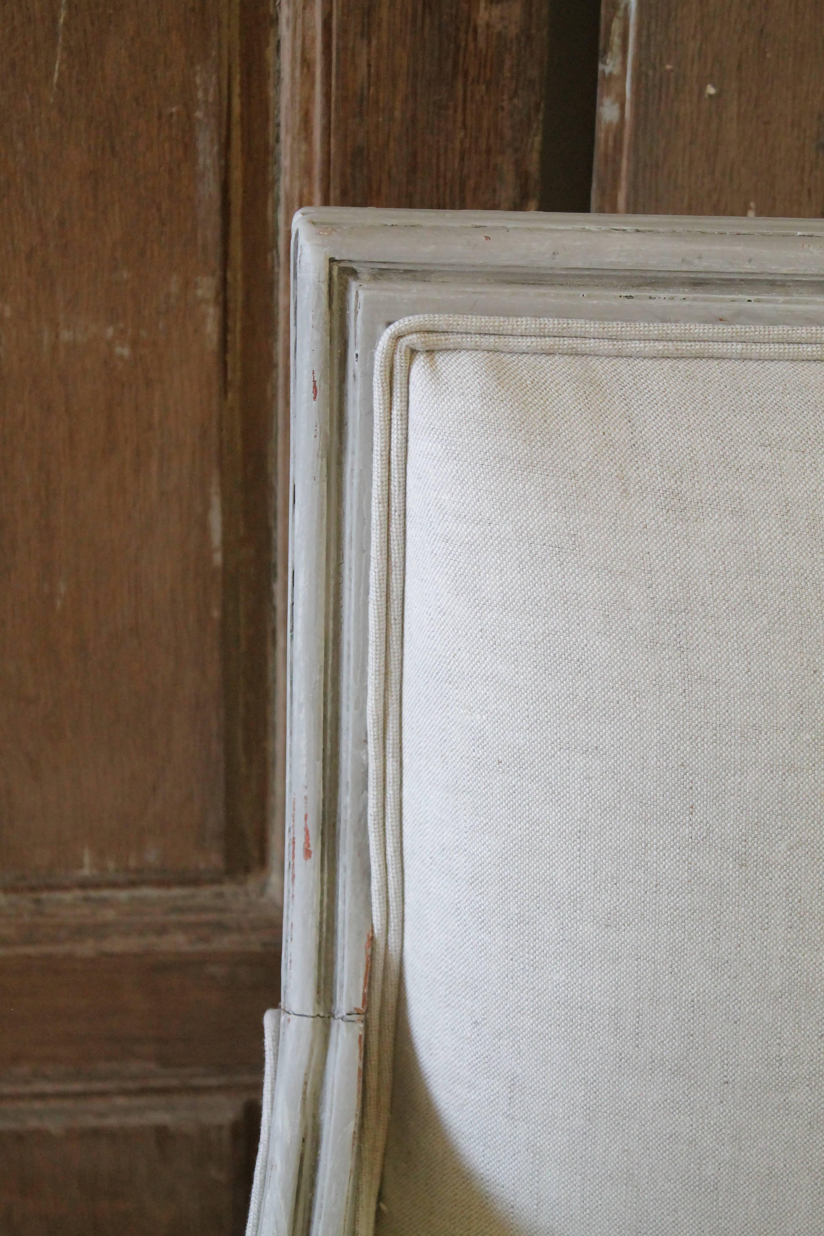 Pair of 20th century painted and upholstered Louis XVI style bergere chairs
Painted in a greige colored paint, with subtle distressed edges, and a carved fluted Louis XVI style leg. We reupholstered these in a greige oatmeal Belgian linen. The seat