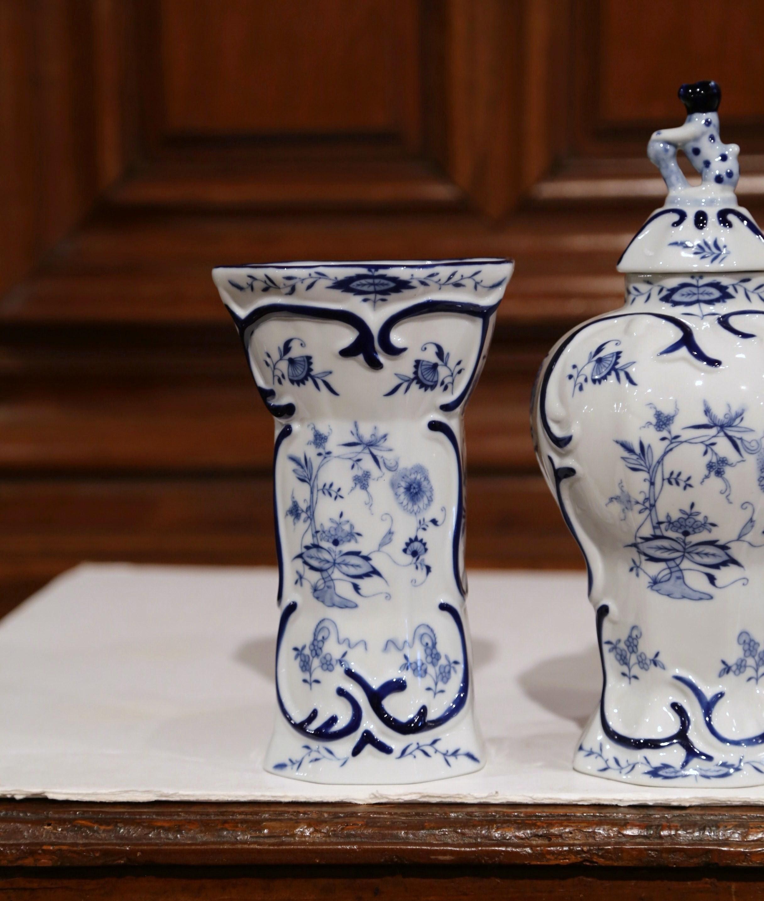 Decorate your mantel or your entryway console with this elegant set of Delft vases. Crafted, circa 1950, the set is made up of three, hand-painted pieces: two vases and a matching jar. All of the elements in the set are decorated with classic floral