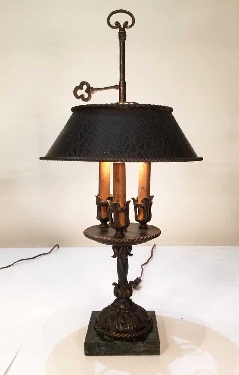 These wonderful pair of Bouillotte Lamps are made out of handwrought iron upon a marble base, circa 1910s-1930s. They each contain three original Candelabra light covers with original candle sleeves and their Tole shades.
   