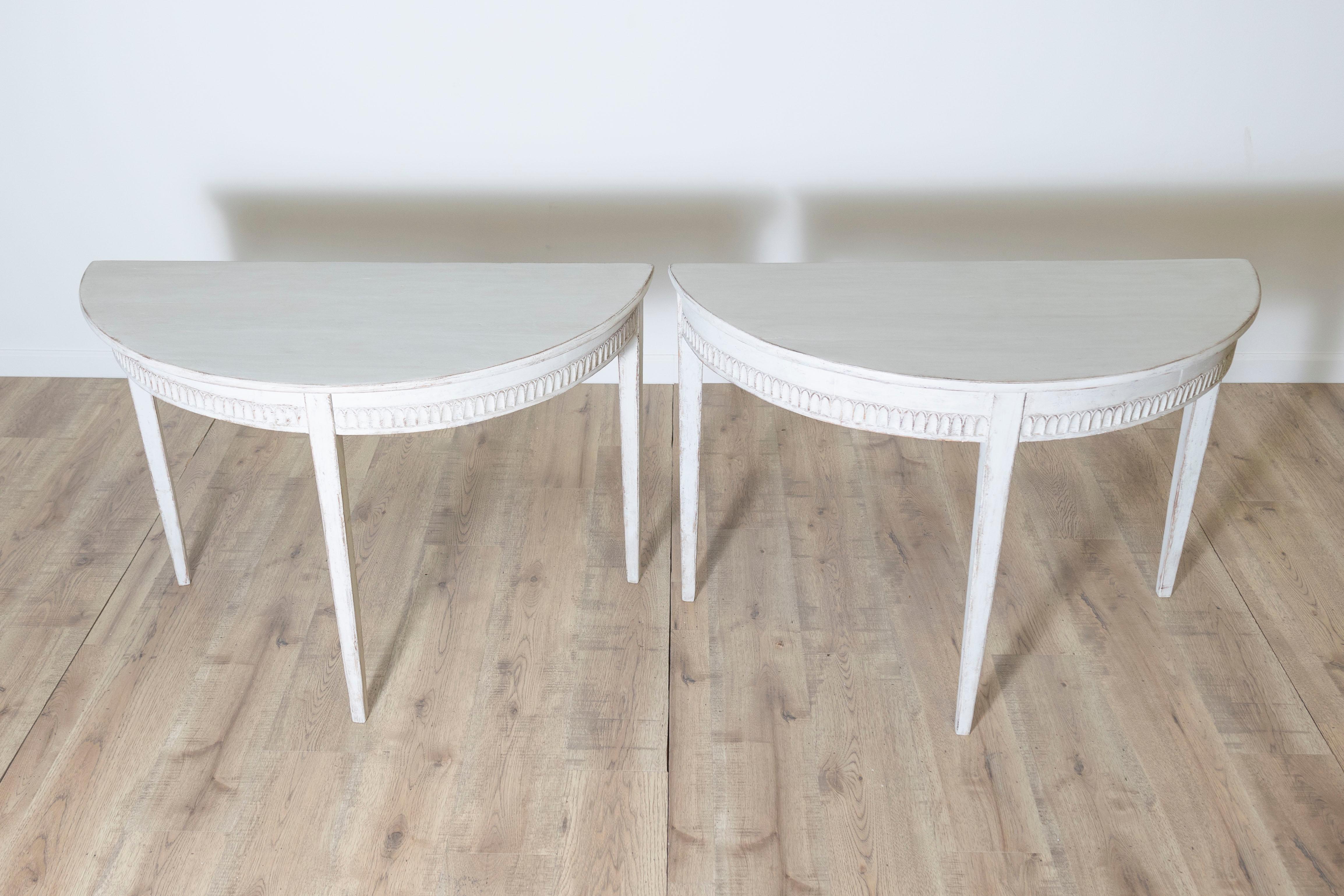 Questa elegante coppia di consolle svedesi del XX secolo è un raffinato esempio di artigianato scandinavo. Costruiti in legno di pino, questi tavoli presentano una finitura verniciata in bianco leggermente consumata, che ne esalta il fascino rustico