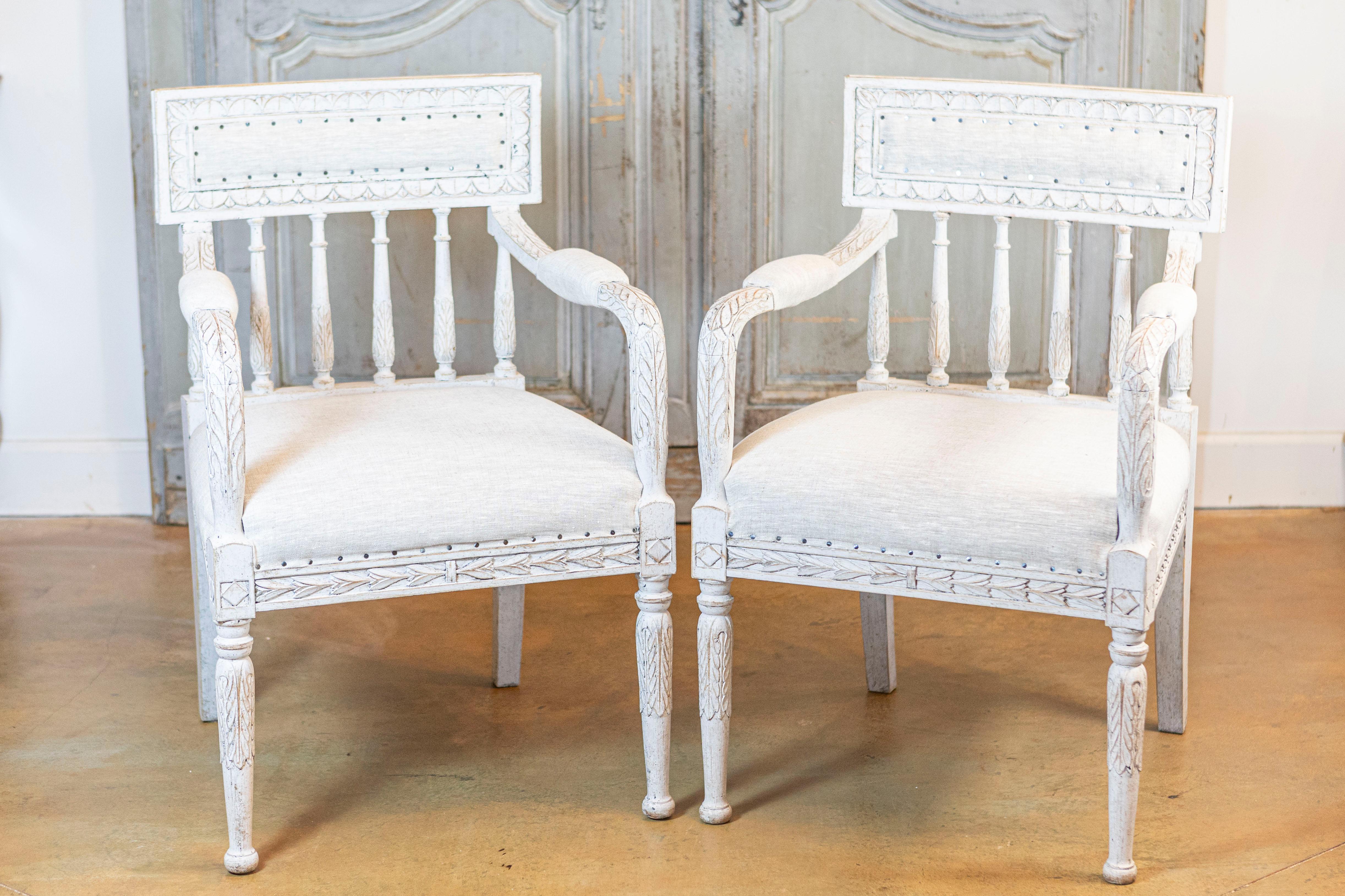 Cette élégante paire de chaises suédoises de style gustavien du XXe siècle incarne la simplicité raffinée et le charme intemporel caractéristiques de cette époque classique du design. Fabriquées en pin peint, un bois traditionnellement privilégié