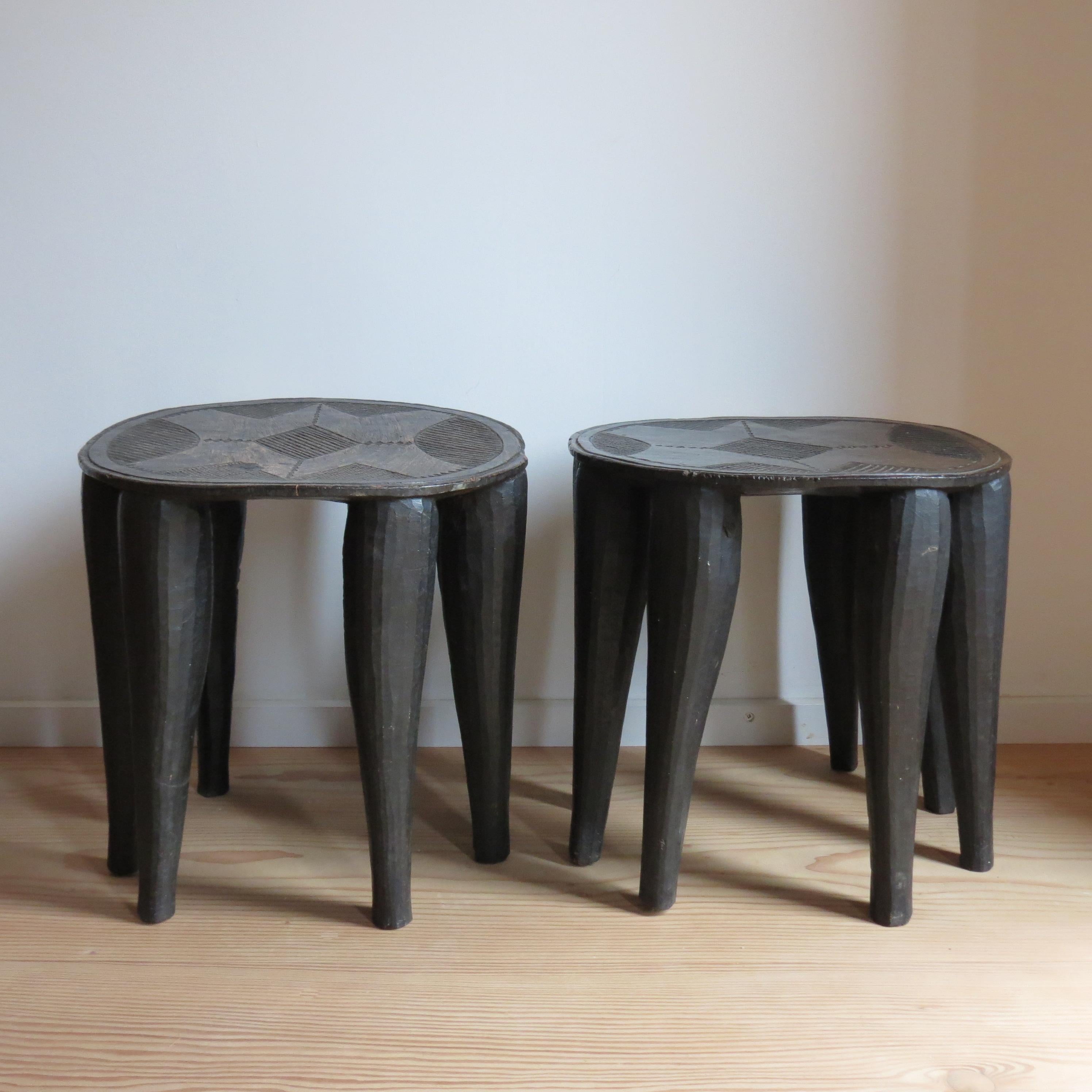 Pareja de maravillosos taburetes tribales Nupe del siglo XX. Cada taburete está hecho de una sola pieza de madera maciza, signos de marcas de publicidad en la parte inferior y en las patas al dar forma a las mesas, con muy buena talla en las tapas,