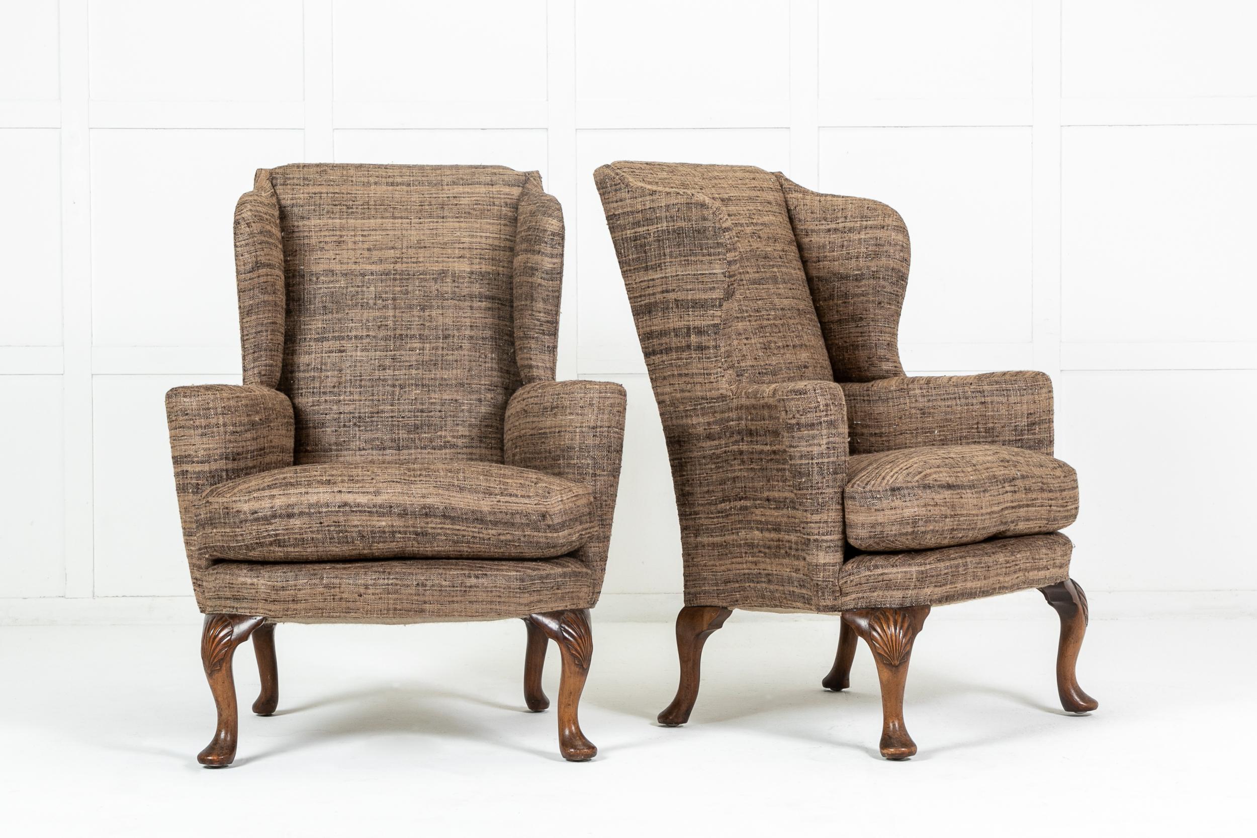 Pair of 20th Century English walnut wing armchairs. Having high backs and winged sides over enclosed, shaped and padded arms. A comfortable padded seat cushion. Standing on cabriole legs decorated with shell carvings.

A nice model in the style of