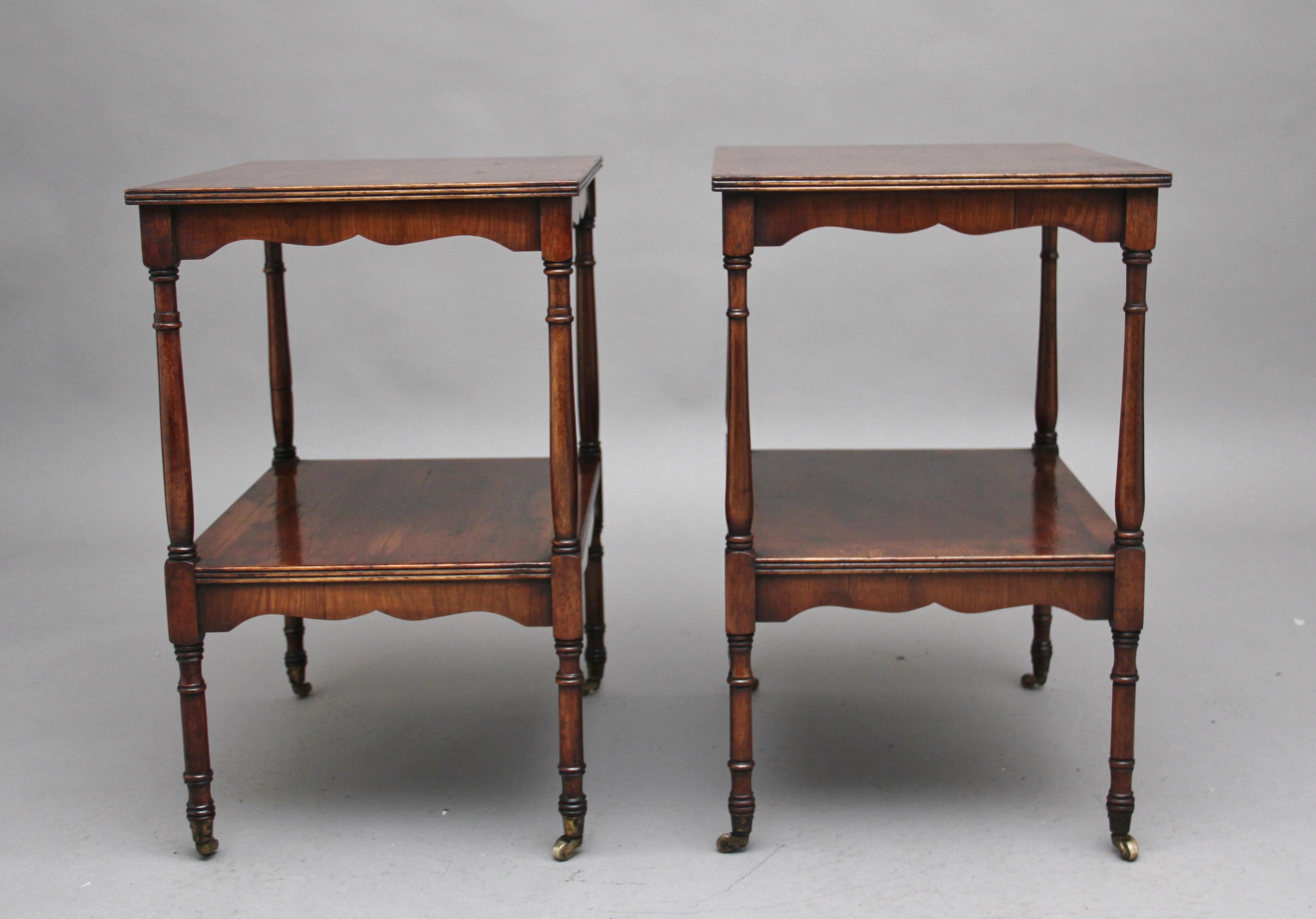 A pair of 20th century two tier yew wood occasional tables, each tier having a reeded edge and shaped apron, elegant turned supports terminating on brass castors, circa 1940.
 