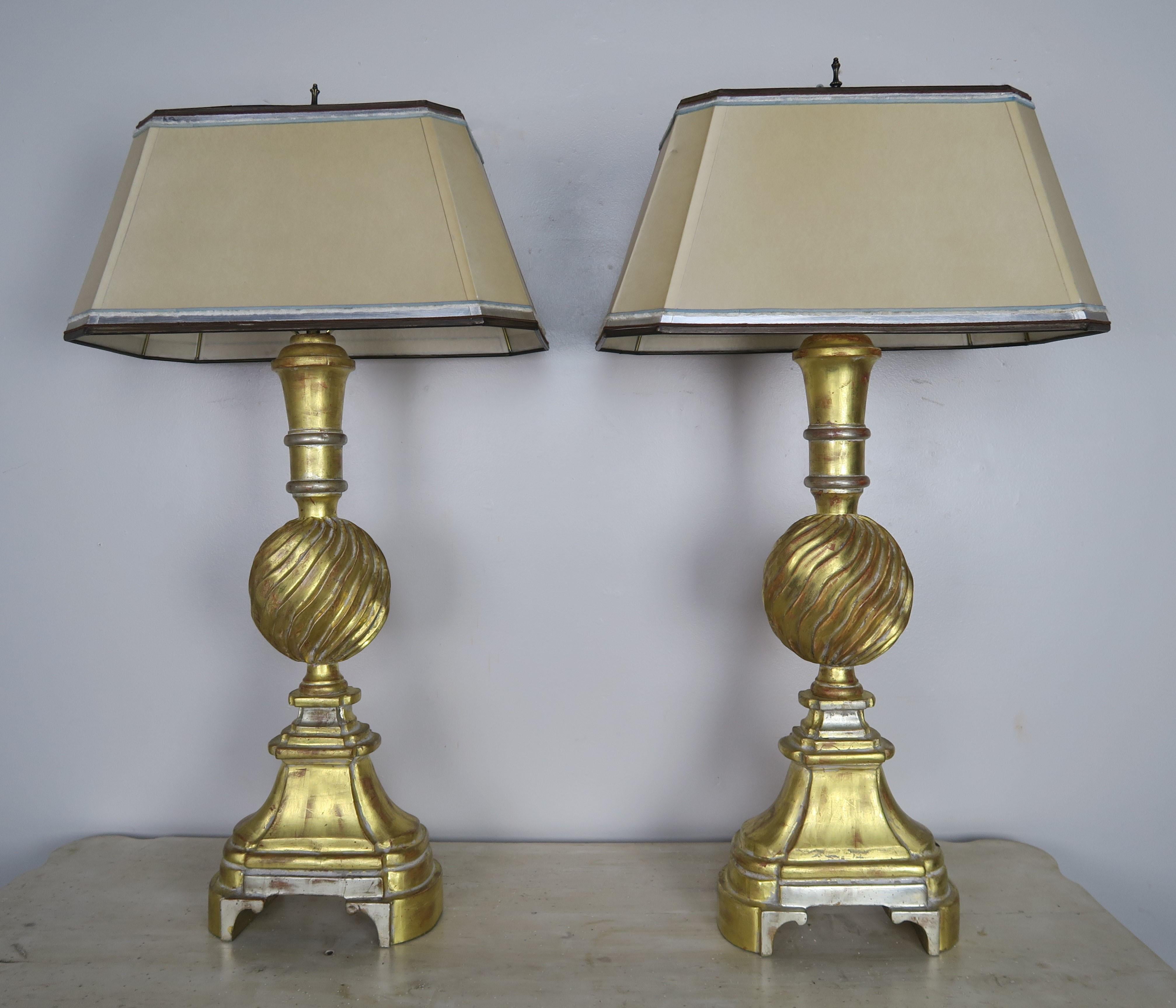 Pair of 20th century 22-karat gold and silver leaf carved wood sculptural shaped lamps. The lamps are newly rewired and crowned with custom hand painted parchment rectangular shaped shades.