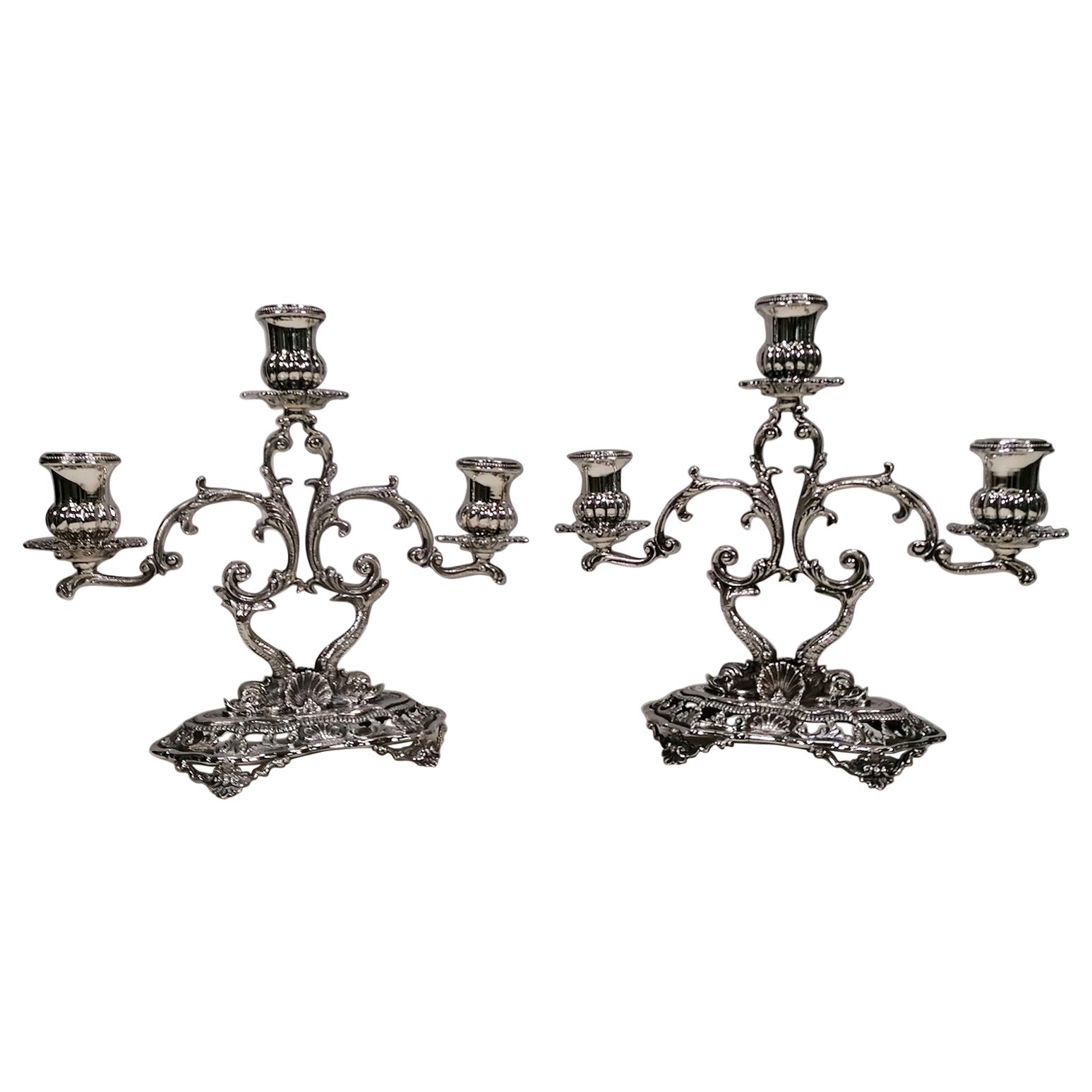 Pareja de candelabros de 3 luces de estilo barroco.
Los candelabros se fabricaron con la técnica de fundición, grabado y cincelado totalmente a mano.
La base oblonga descansa sobre 4 pies y está perfilada y perforada con diseños de voluta y concha,