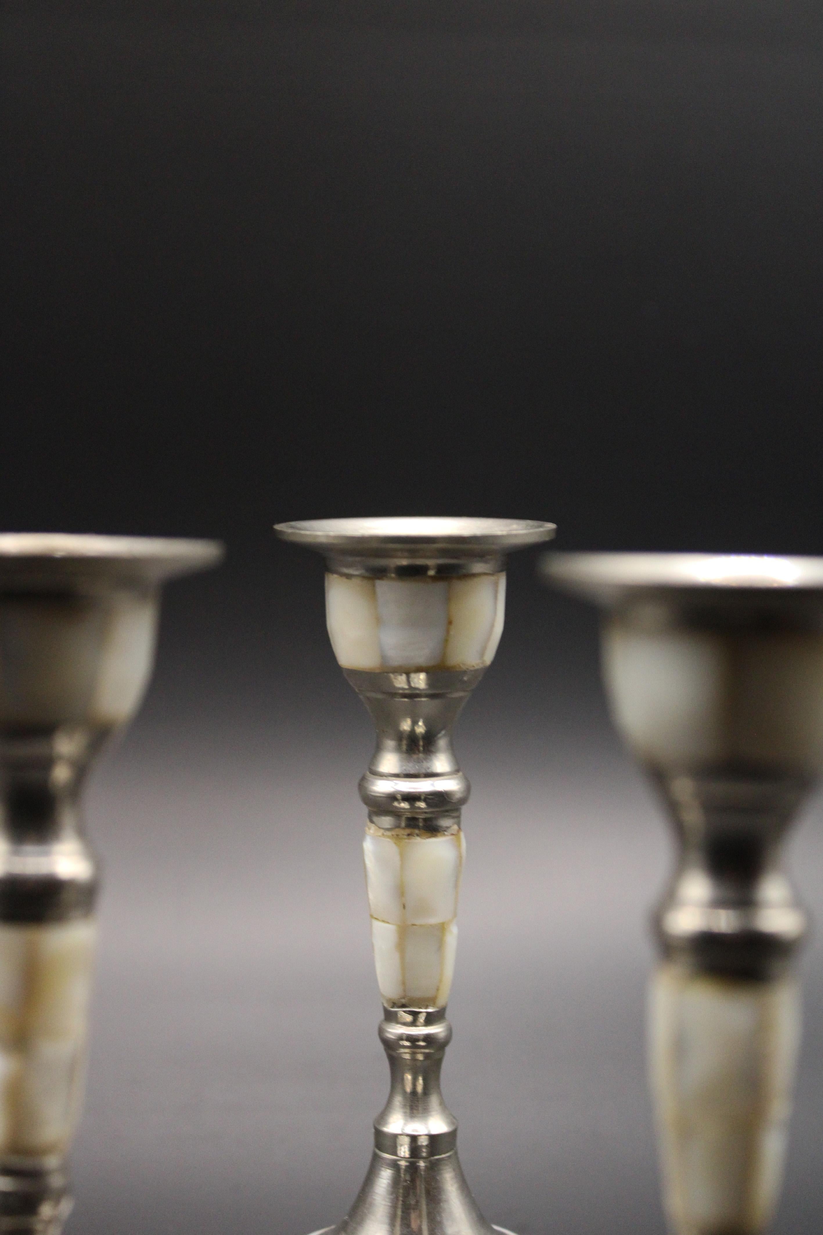 This exquisite set of three silver-plated brass candlesticks, crafted in France circa 1970, is a true testament to the beauty of mid-20th-century craftsmanship. The combination of silver-plated brass and the delicate inlays of mother-of-pearl