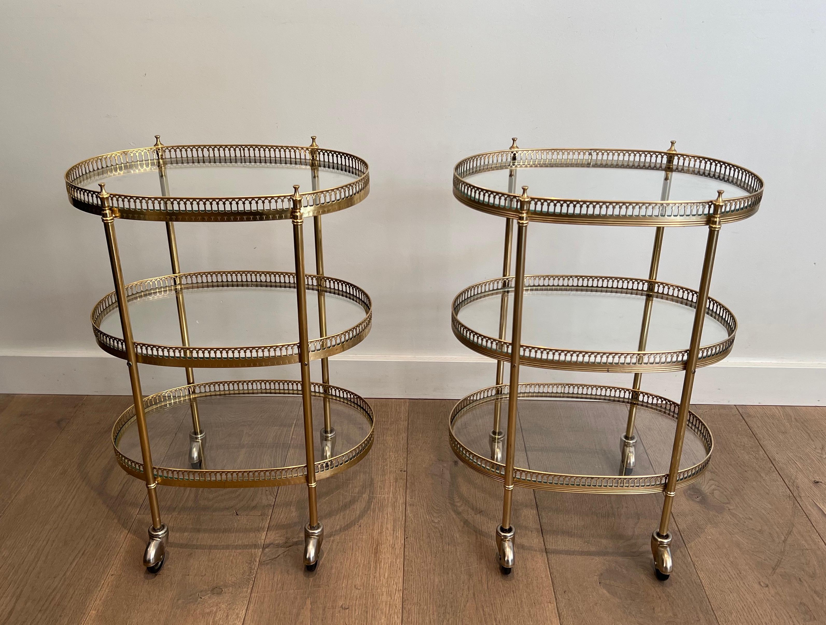 This very nice and rare pair of neoclassical style 3 tiers oval drinks trolley is smade of brass with 2 glass shelves. This is a French work in the style of Maison Jansen. Circa 1940.