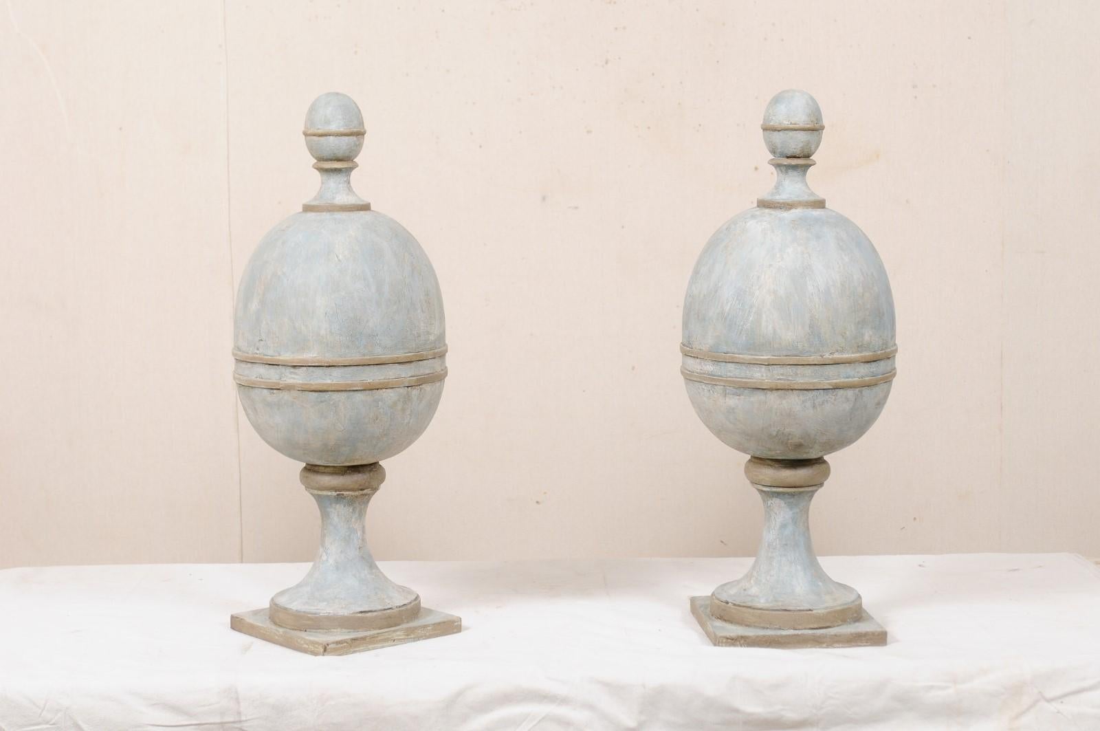 A pair of artisan crafted solid wood finials, standing 32 inches in height. This contemporary pair of American artisan created finials have egg-shaped bodies with upper egg-shaped finial adornment at their tips, and raised upon rounded pedestal