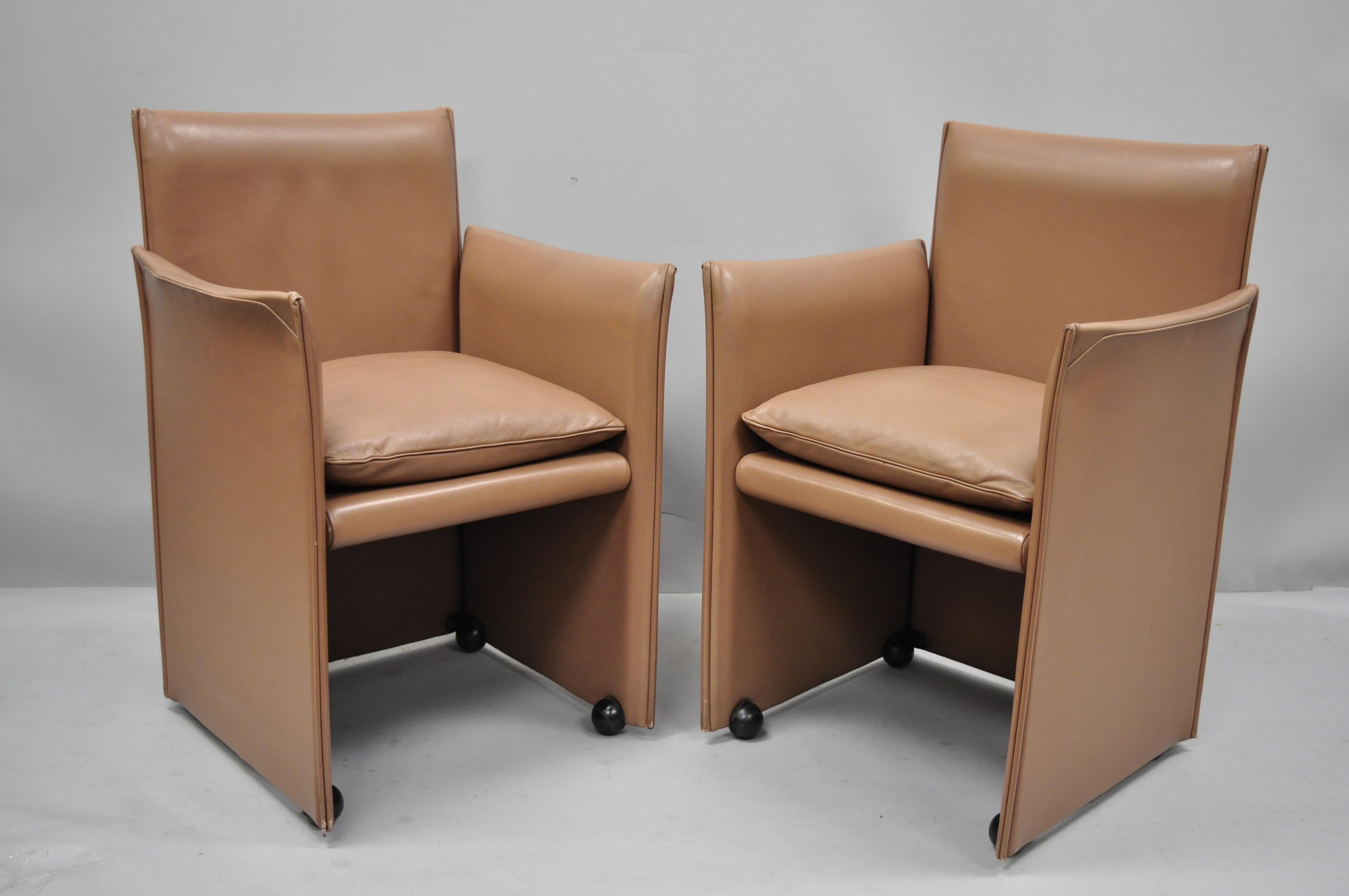 Pareja de sillones 401 break de Mario Bellini para Cassina de cuero cobrizo. El listado incluye armazón completo forrado de cuero, ruedas rodantes, etiqueta original, líneas modernas y limpias, forma elegante y escultural, hacia finales del siglo