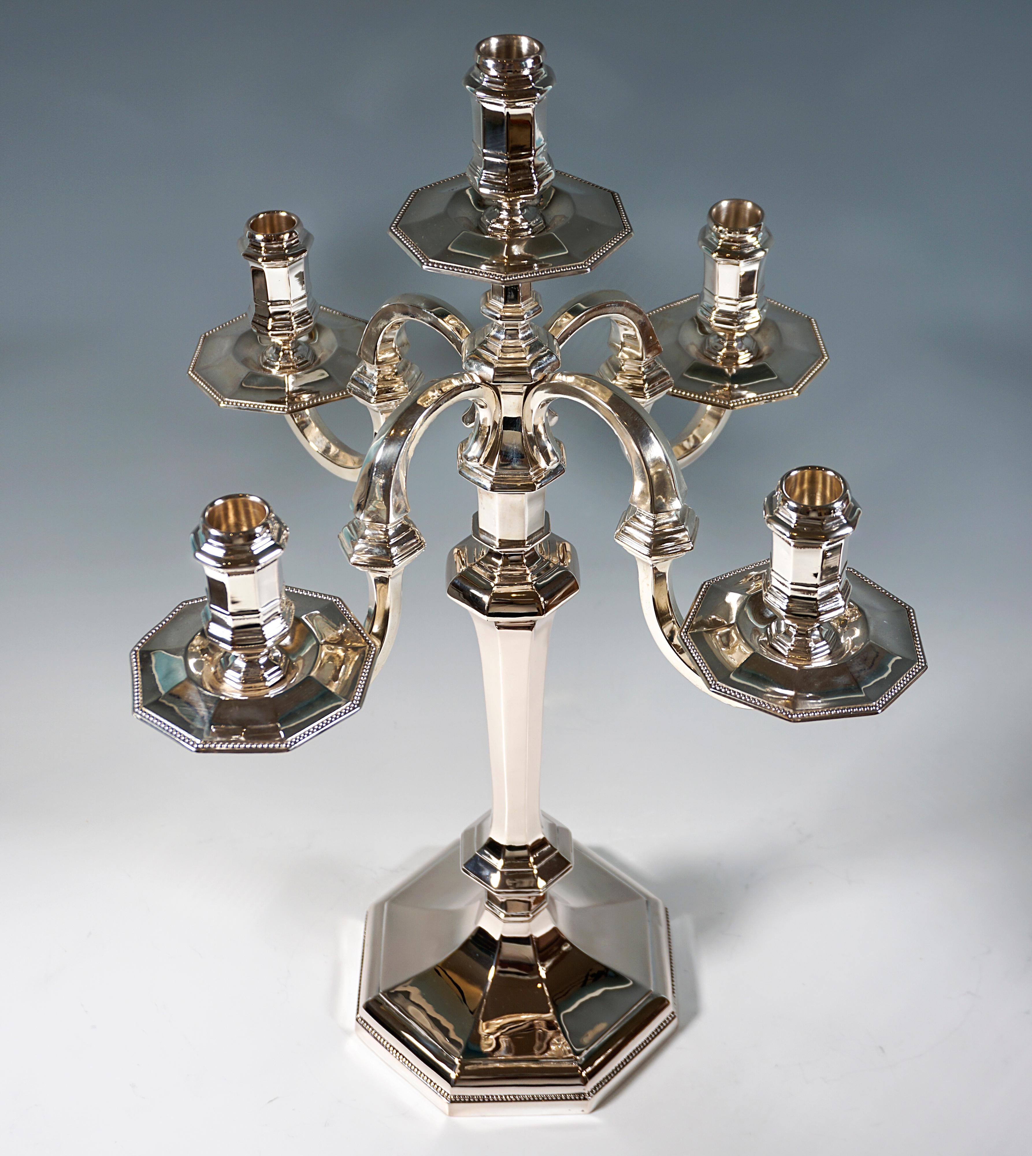 Two elegant five-flame candleholders on an octagonal stepped foot with pearl band border, raised in the centre and opening into a 
shaft with octagonal cross-section, octagonal bead ring in the lower area of the shaft, widening wall and forming a