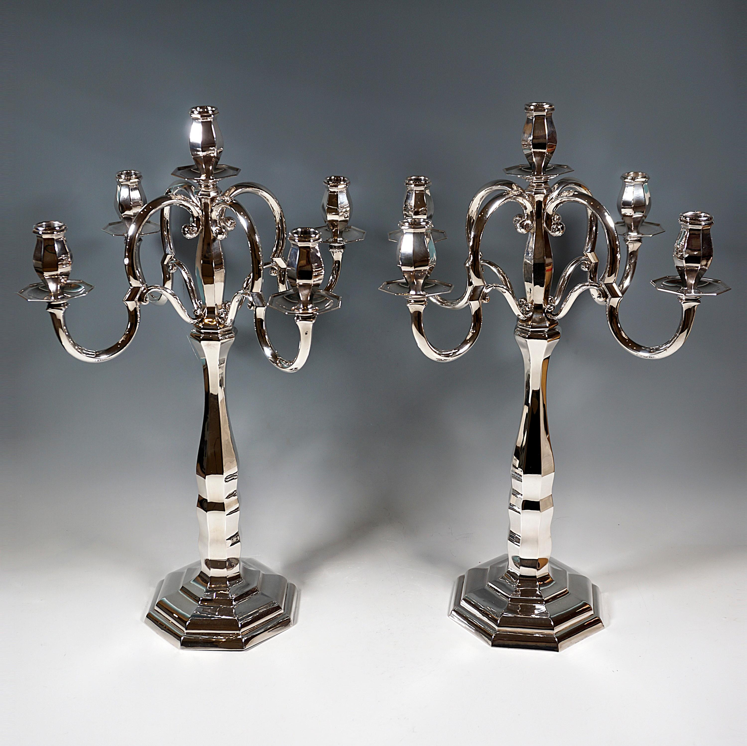 Two five-flame candelabras of simple elegance on an octagonal, stepped foot, raised in the middle and ending in a shaft with an octagonal cross-section, in the lower area of the shaft the wall is slightly wavy, converging and widening again,