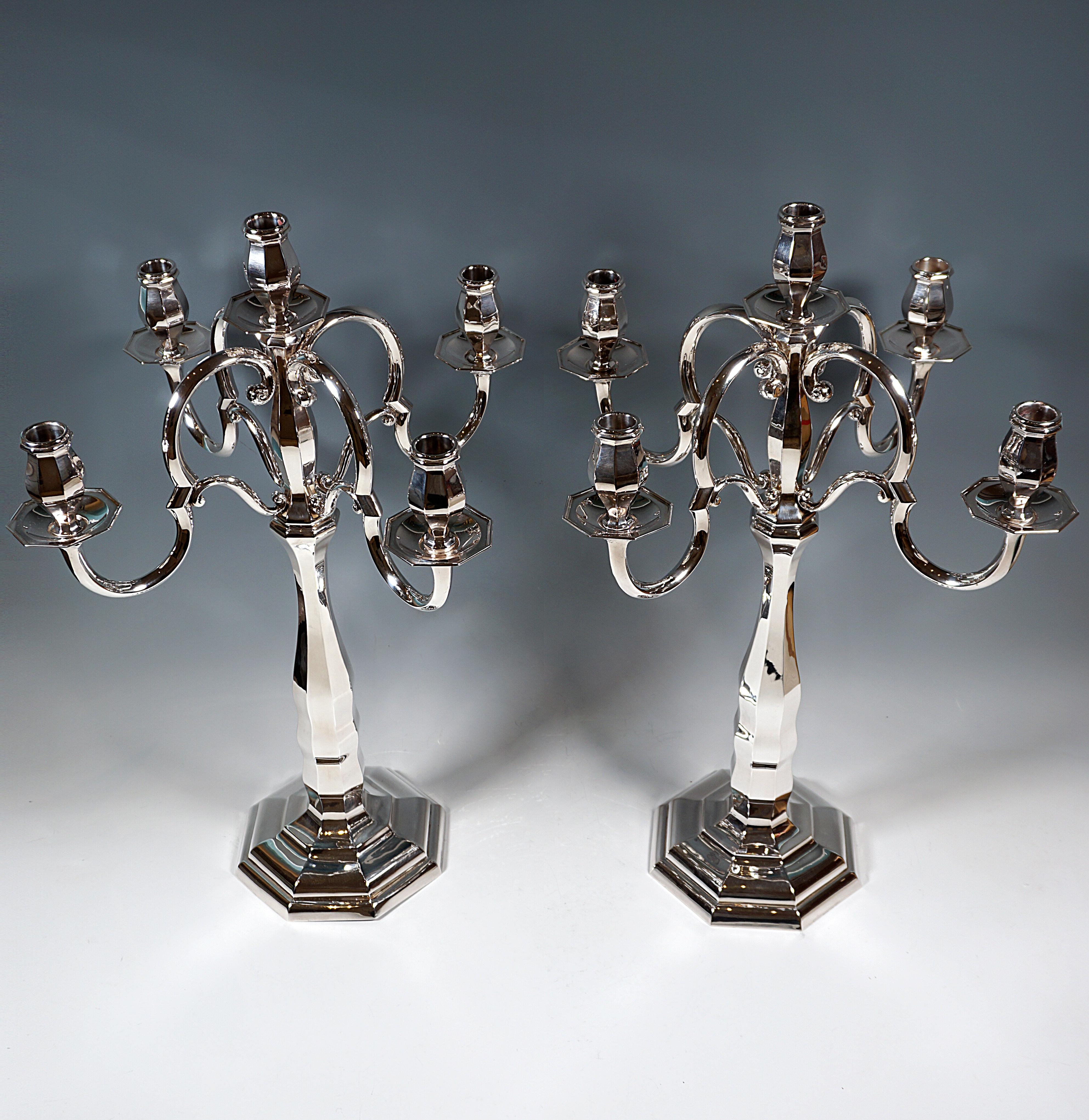 Two five-flame candelabras of simple elegance on an octagonal, stepped foot, raised in the middle and ending in a shaft with an octagonal cross-section, in the lower area of the shaft the wall is slightly wavy, converging and widening again,