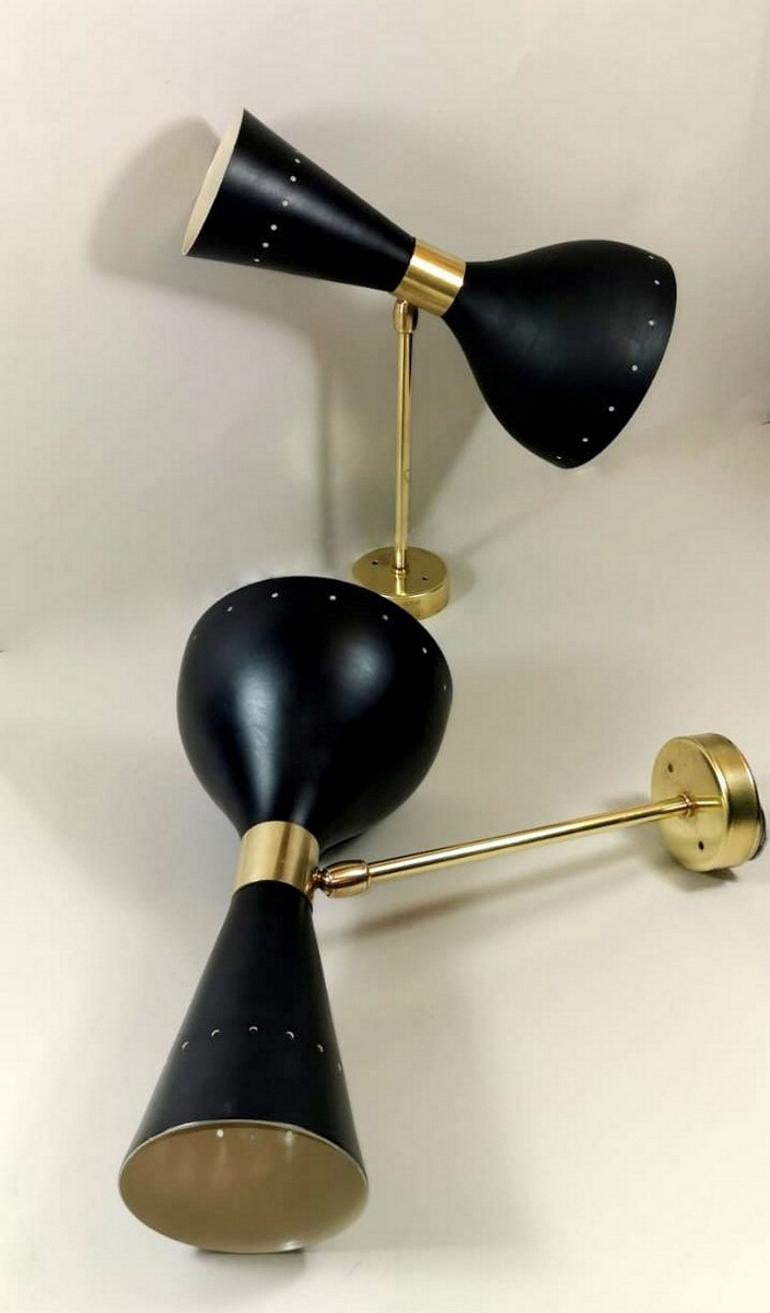 Pair of appliques in brass and black painted metal; they have two light attachments, one in the round parabola and the other in the truncated cone part; in the middle have a joint that allows you to rotate them 360° according to your wishes or