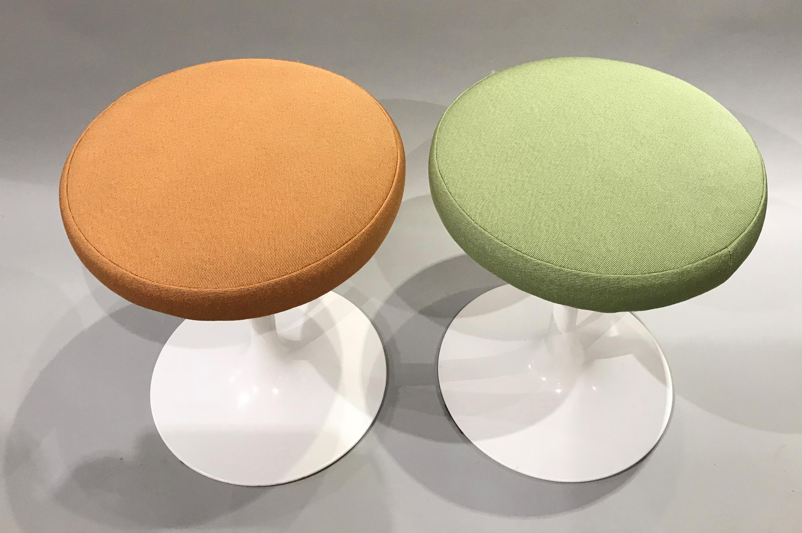 A fine pair of Knoll tulip stools with orange and green upholstered cushions and white painted aluminum base, originally designed by Eero Saarinen in the mid 20th century. This pair circa 2007 celebrates the 50th anniversary of this style with a