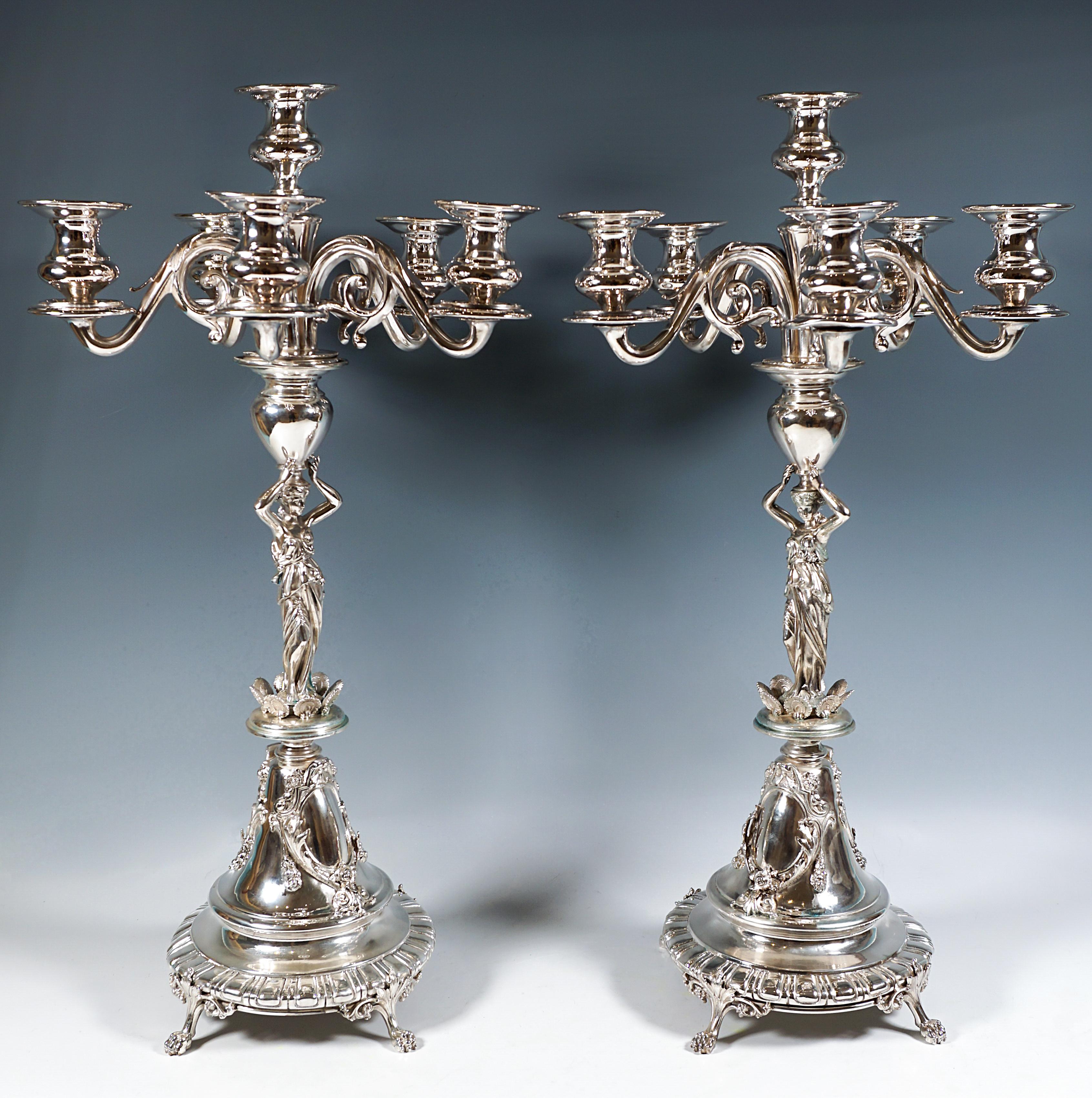 Pareja de altos candelabros festivos de plata sobre un soporte escalonado en forma de embudo, asentados sobre cuatro pies de león con decoración de voluta y foliadas, decoración plisada radial en el borde inferior, el acanalado y el cono del pie de