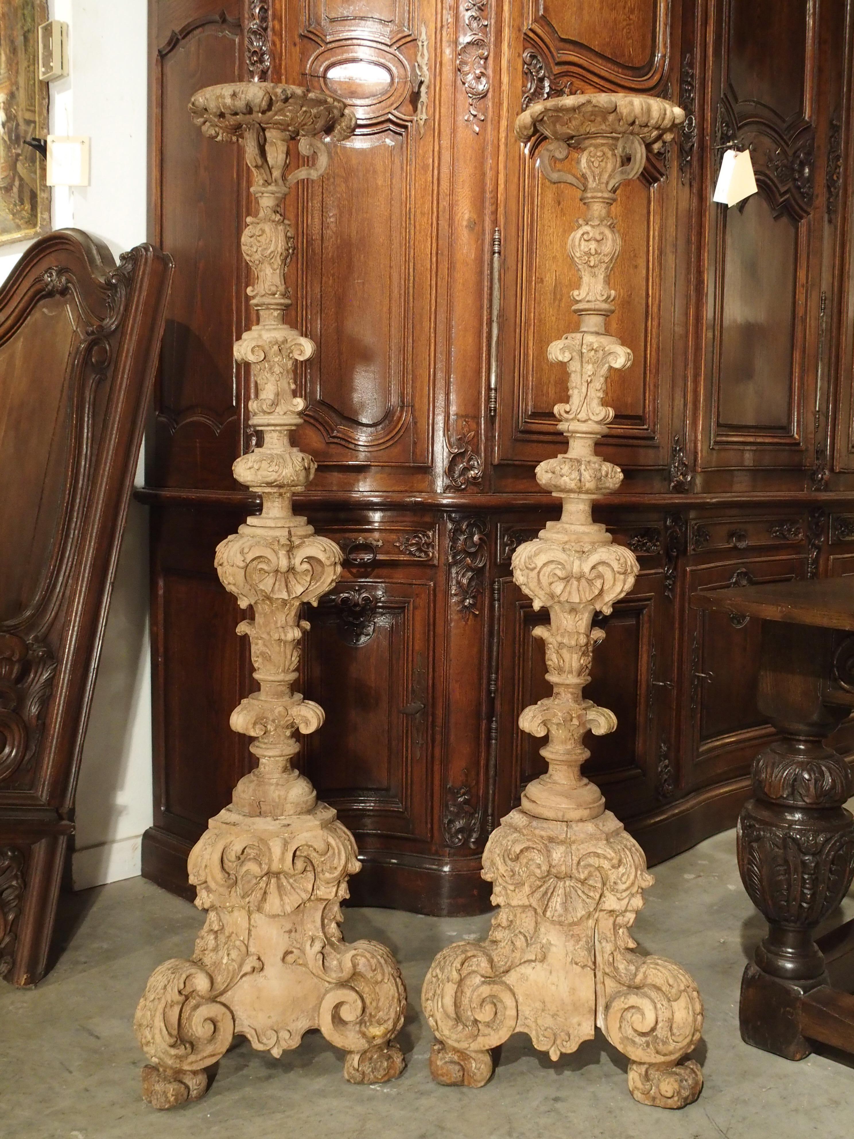 These tall, light walnut wood candlesticks date to the mid to late 1600s. They were likely commissioned as altar candlesticks for a French chapel. Their shape is narrow and elegant, but widens slightly as you go down to the bottom. The motifs are