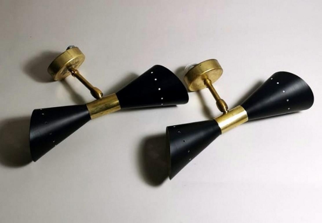 Pair of wall sconces in brass and metal painted black and cream white inside; they have two connections for direct and indirect light; in the middle, they have a joint that allows you to rotate them 360° according to your wishes or your furnishing