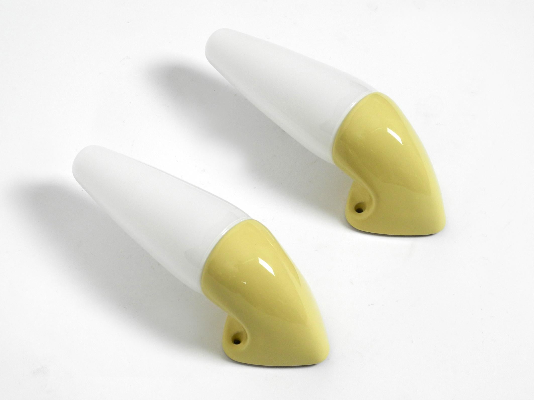 Set of two yellow green glazed porcelain bathroom wall lights.
Designer is Sigvard Bernadotte for IFÖ. Made in Sweden in the late 1960s.
Minimalist glass design. Ceramic bases and sockets.
Suitable as wall lamps for all living areas and very