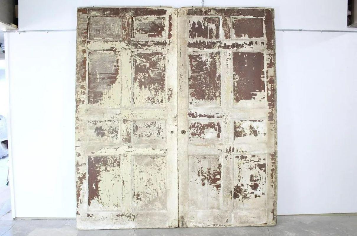 Pair of 9' 20th century antique painted white pocket doors. Very large pocket doors have 8 panels each, have been painted white; paint is distressed and chipping heavily. Beautiful and substantial doors if restored.