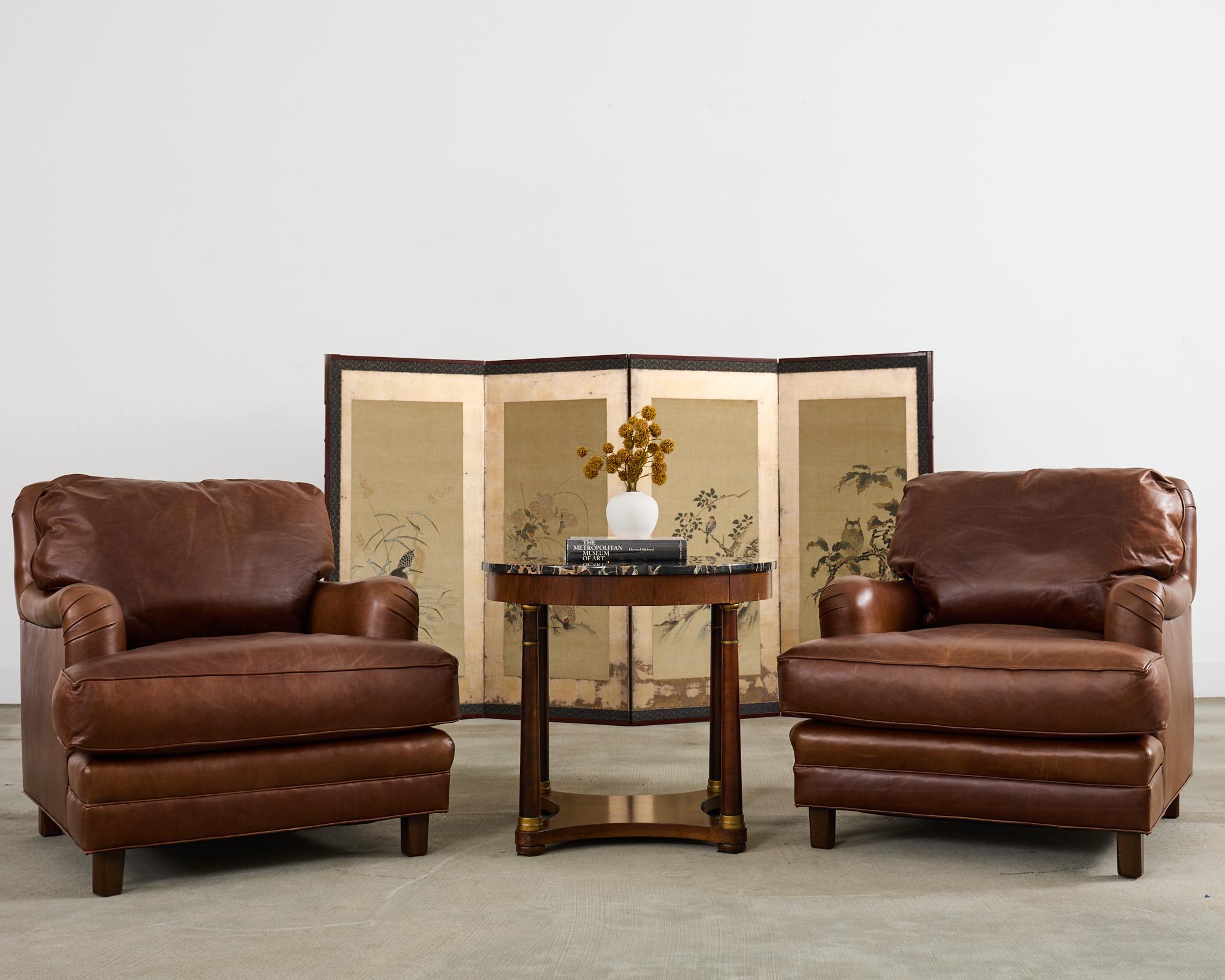 Handsome pair of cigar leather club chairs or lounge chairs attributed to A. Rudin Hollywood, CA model #594. The chairs feature a large hardwood frame with gracefully curved, rolled English arms. The generous seat has a fitted loose seat and back