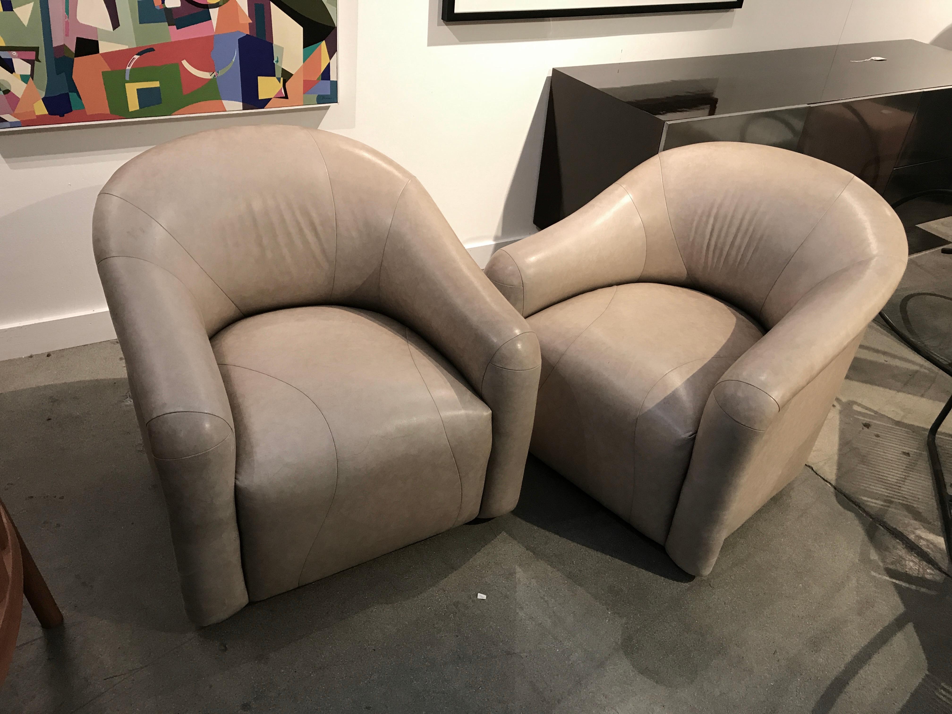 A nice neutral colored pair pf A. Rudin swivel chairs upholstered in leather or we believe lamb skin. The Lambskin or leather has signs of use, with some marks scratches, scuffs and discoloration. We have pictured the worst. Both of these are