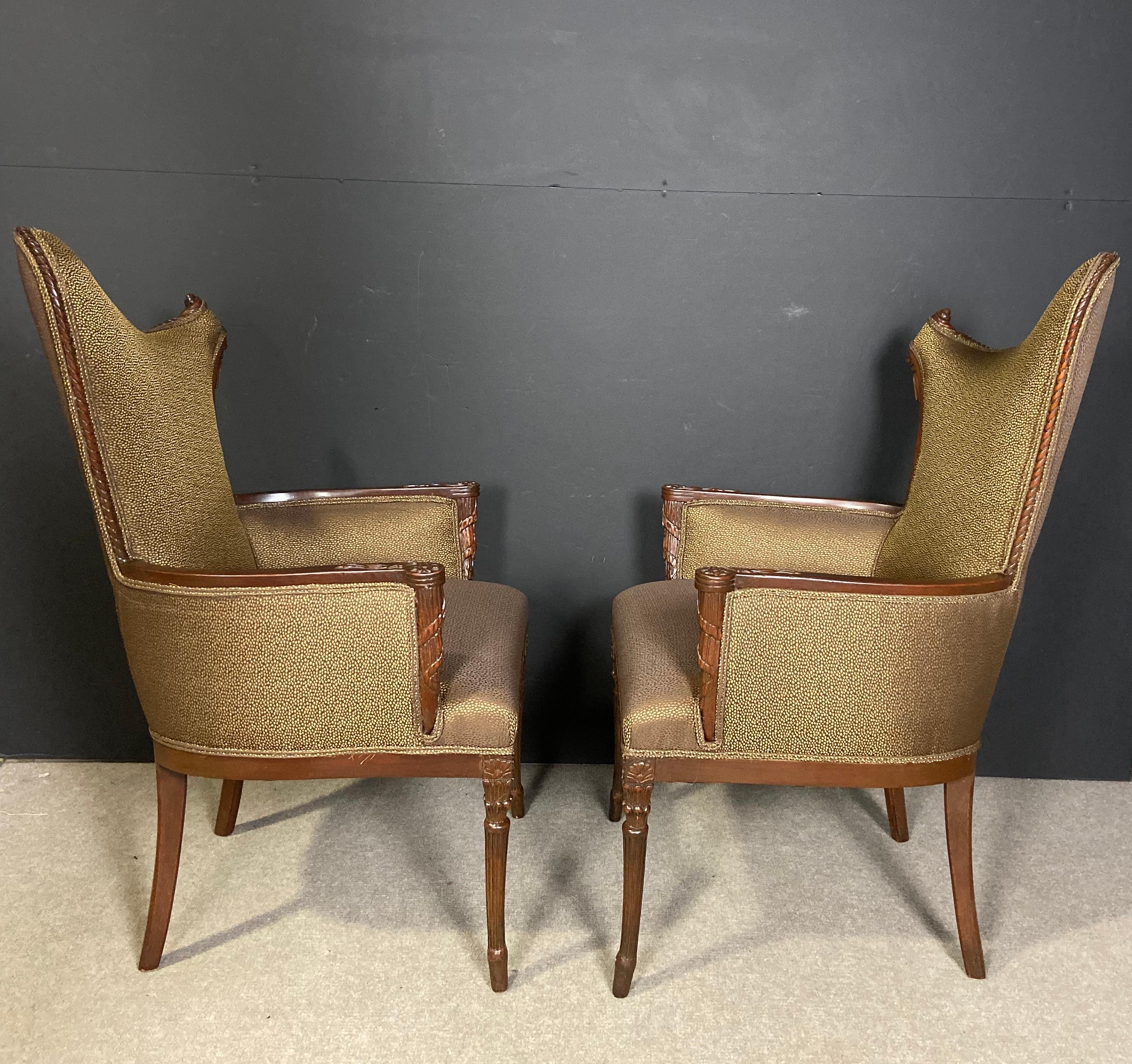 Pair of unusual form midcentury Hollywood Regency hand carved left and right opposing side chairs/armchairs. Upholstered in a wonderful gold and brown fabric.