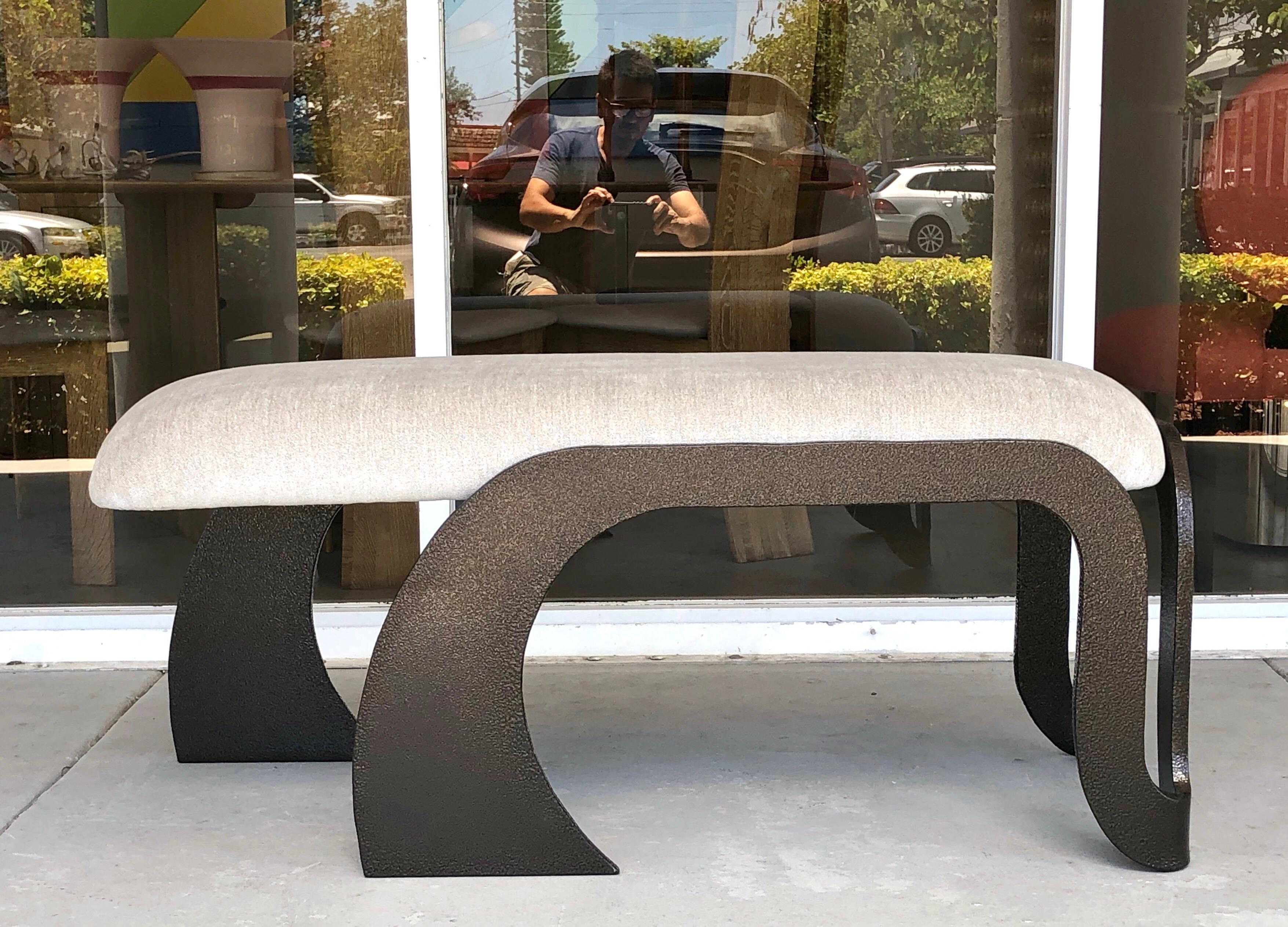 A pair of abstract benches. The frames are heavy steel with a thick glass like enamel finish in what resembles hammered bronze. Cantilevered upholstered seats. Available individually or as a pair.