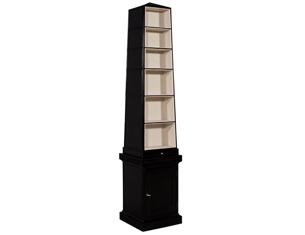 Pair of abstract Obelisk bookshelves by Baker Furniture. Solid mahogany construction, featuring custom two-tone finish. Bookcases contain 6 shelves on both the front and rear of the cabinets. Completed with a pull out drawer, bottom storage