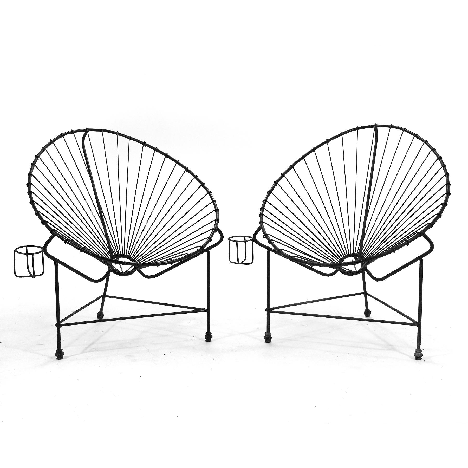 A iconic Mexican modern design, the Acapulco Chair is a light, breezy chair perfect for the patio, poolside, or the beach. This striking vintage pair is uncommon for their fixed wire rod supports rather than nylon cord, their attached cup holders,