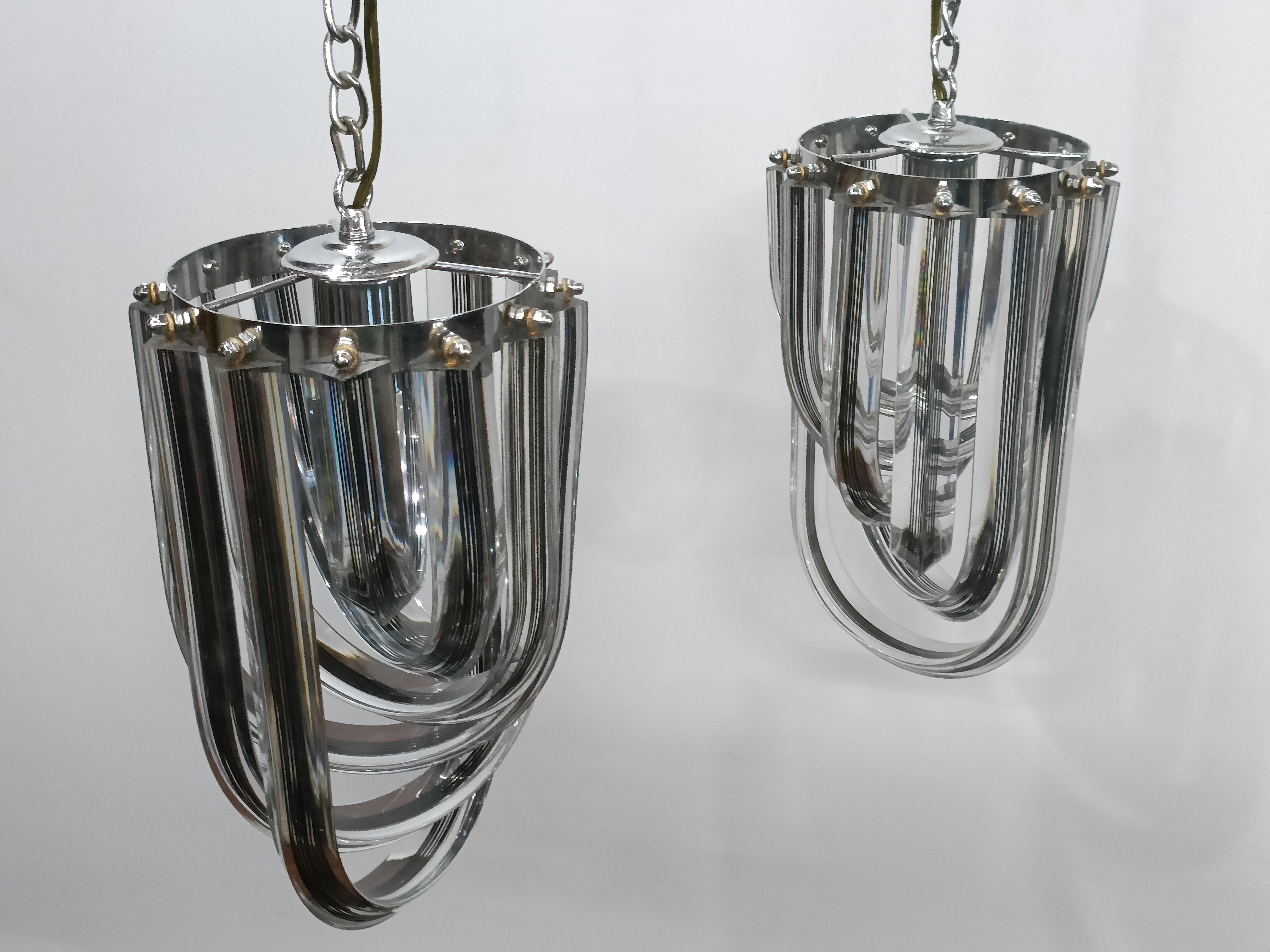 A pair of acrylic pendants with chrome hardware.  Clear with black interior stripes and each loop swivels to gain access to the bulb holder.  These are originally European from the 1970's--very atomic style.  Rewired for American use and takes a