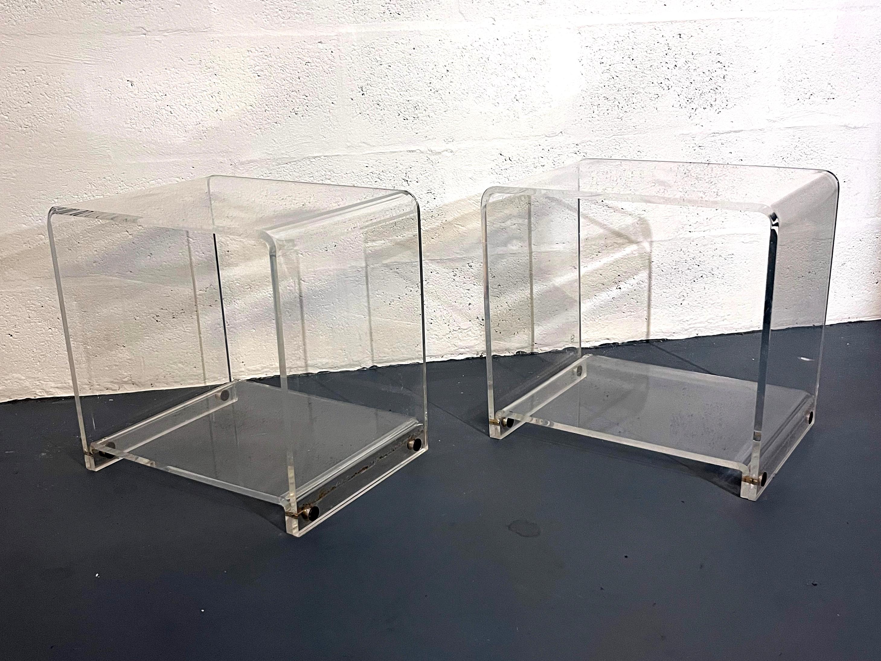 Elegant and minimalist pair of acrylic side tables, in the style of Les Invisibles du Marais, France, circa 1970s.
Each table is crafted from a single sheet of bent clear Lucite, forming a seamless U-shape with soft edges and a subtle sculptural