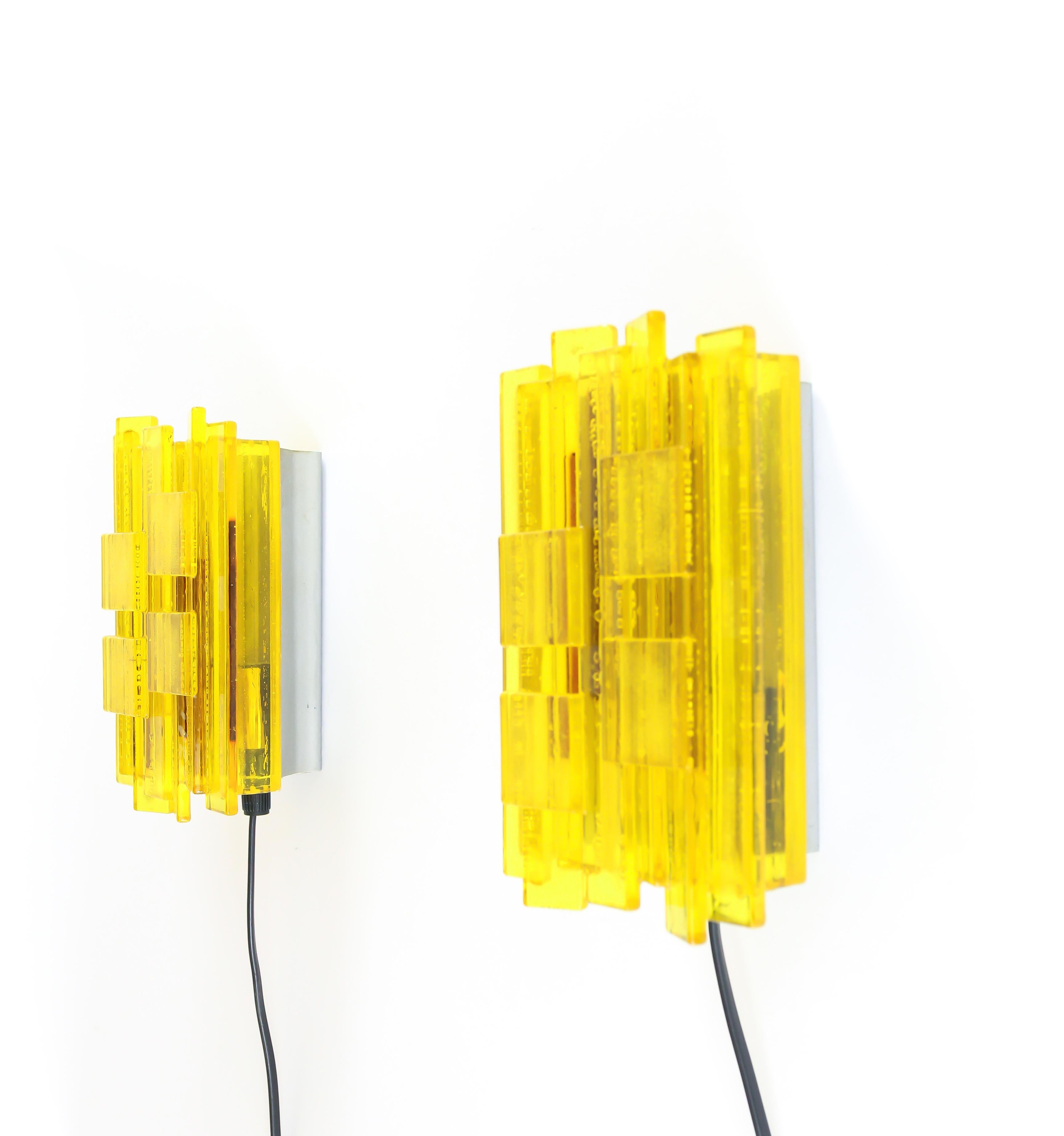 A pair of yellow handmade acrylic wall lamps. The sconces were designed by Claus Bolby and manufactured by his own company, Cebo Industri. By experimenting, Bolby discovered a technique allowing him to introduce bubbles into the acrylic, which adds