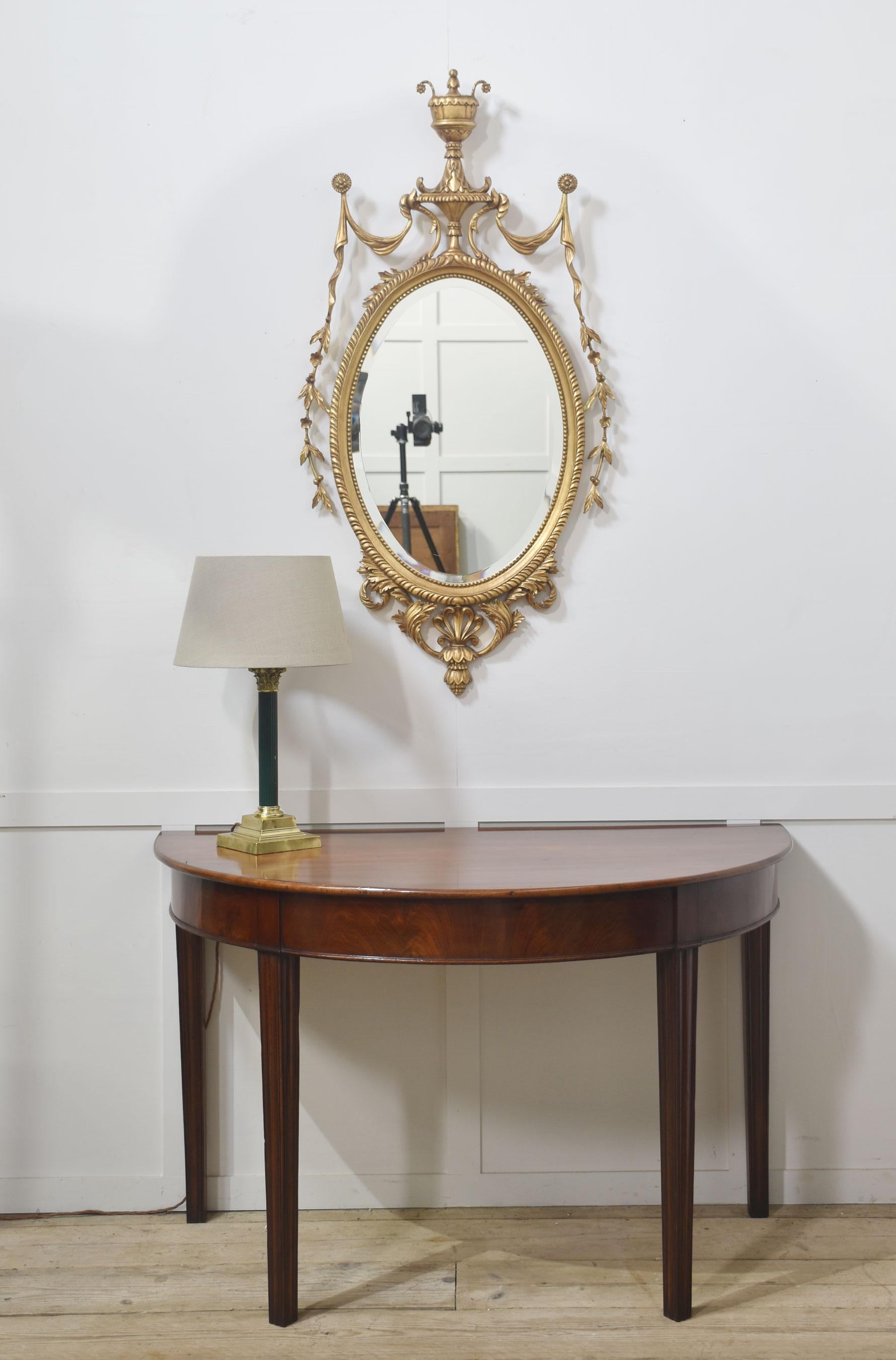 Pareja de espejos de pared ovalados de madera dorada tallada estilo Adam Británico en venta