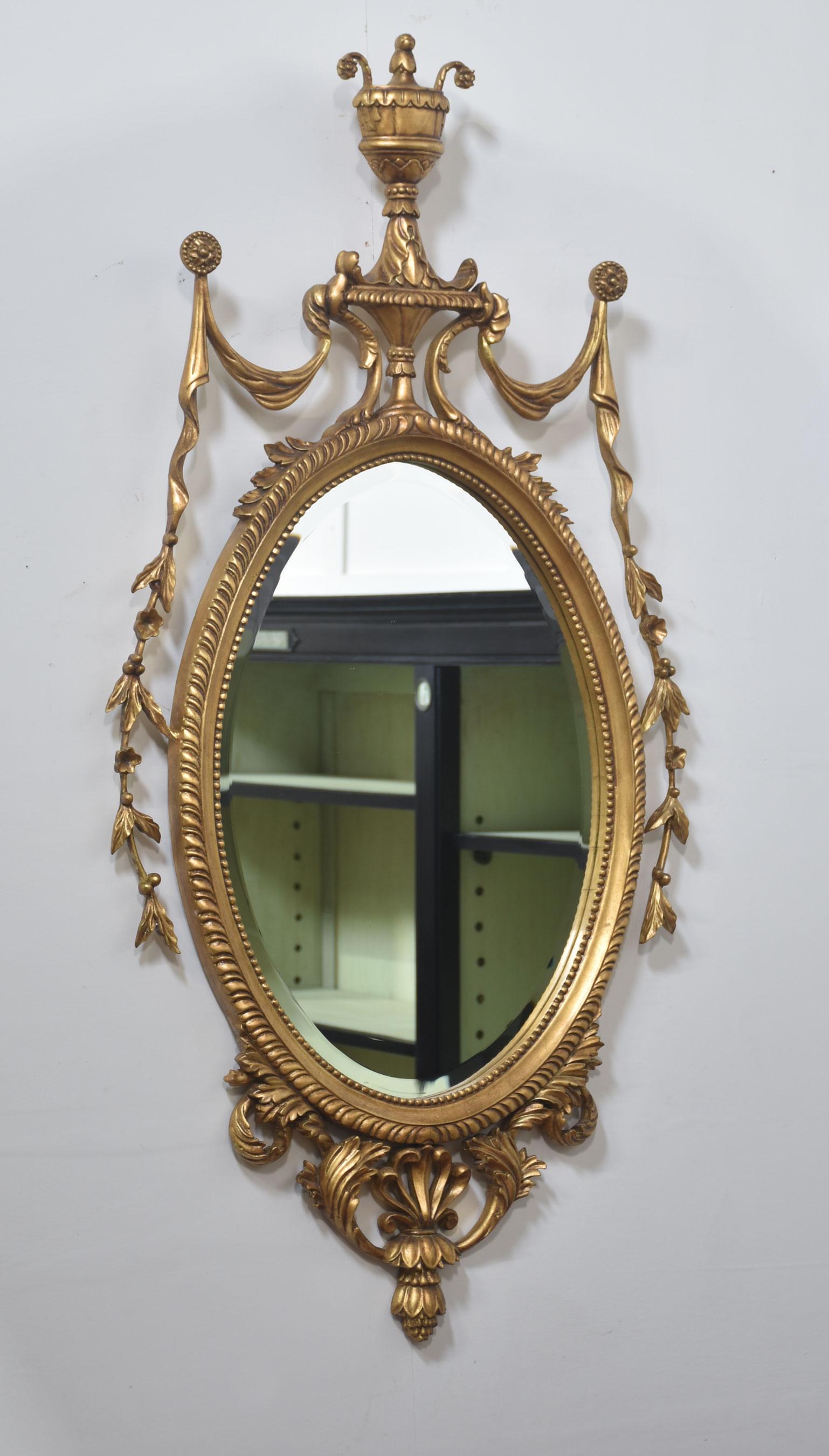 Pareja de espejos de pared ovalados de madera dorada tallada estilo Adam siglo XX en venta