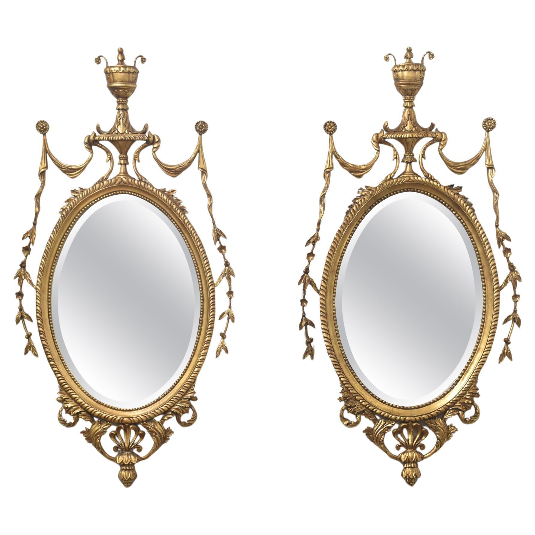 Pair of Adam style carved giltwood oval wall mirrors