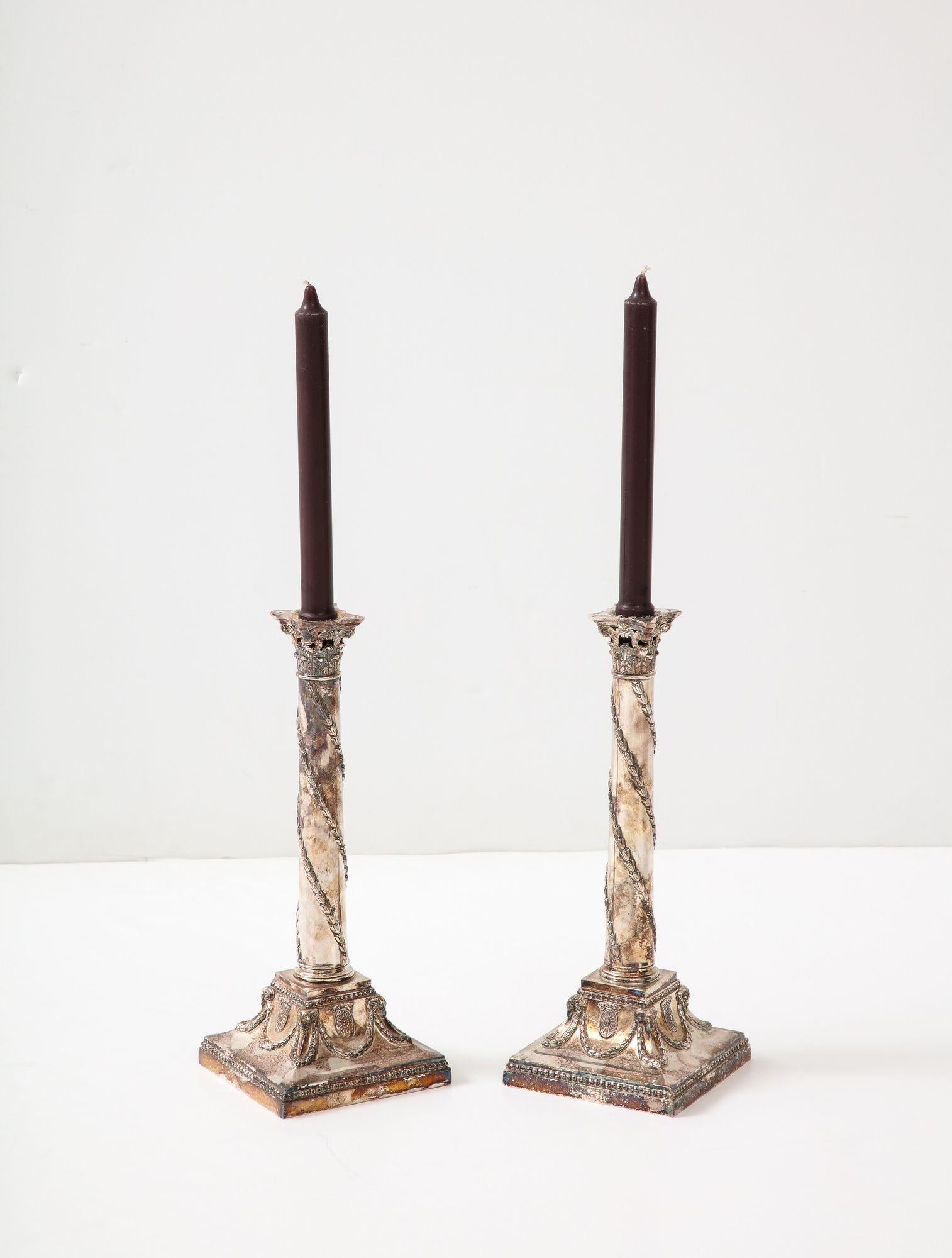 Buona coppia di candelieri d'argento edoardiani in stile Adams, con capitelli corinzi traforati su colonne con viti a spirale di fiordaliso, la base ornata da ghirlande e patere.