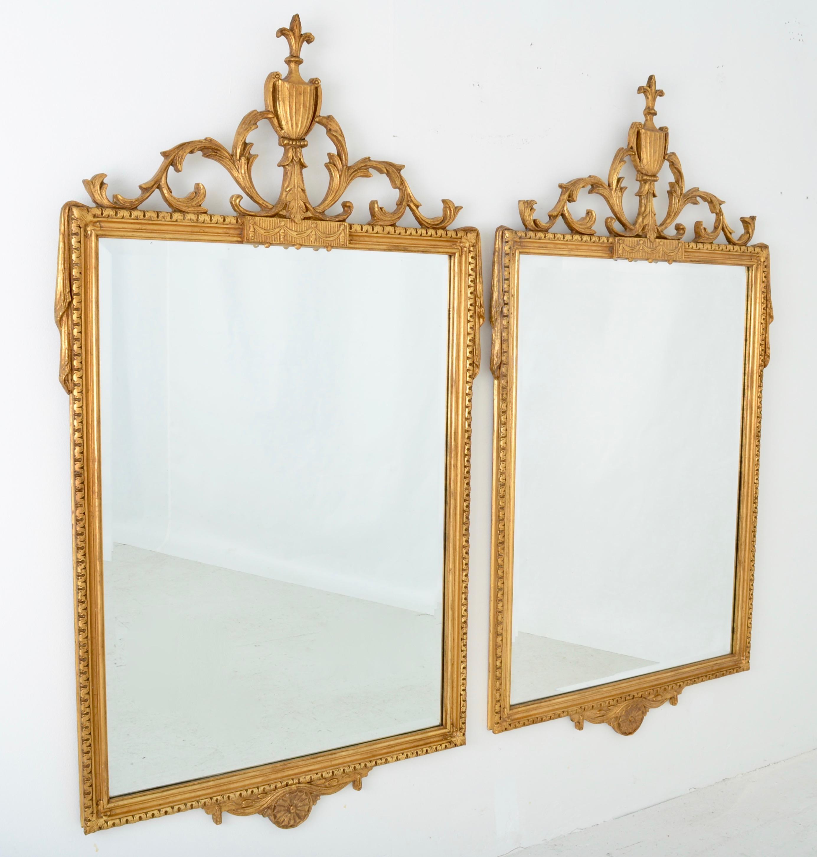 A pair of Adams style mirrors made for Friedman Brothers, circa 1950s in Italy. They feature bevelled glass and parcel gilded hand carved wood frames. Very fine condition. Original labels on verso.