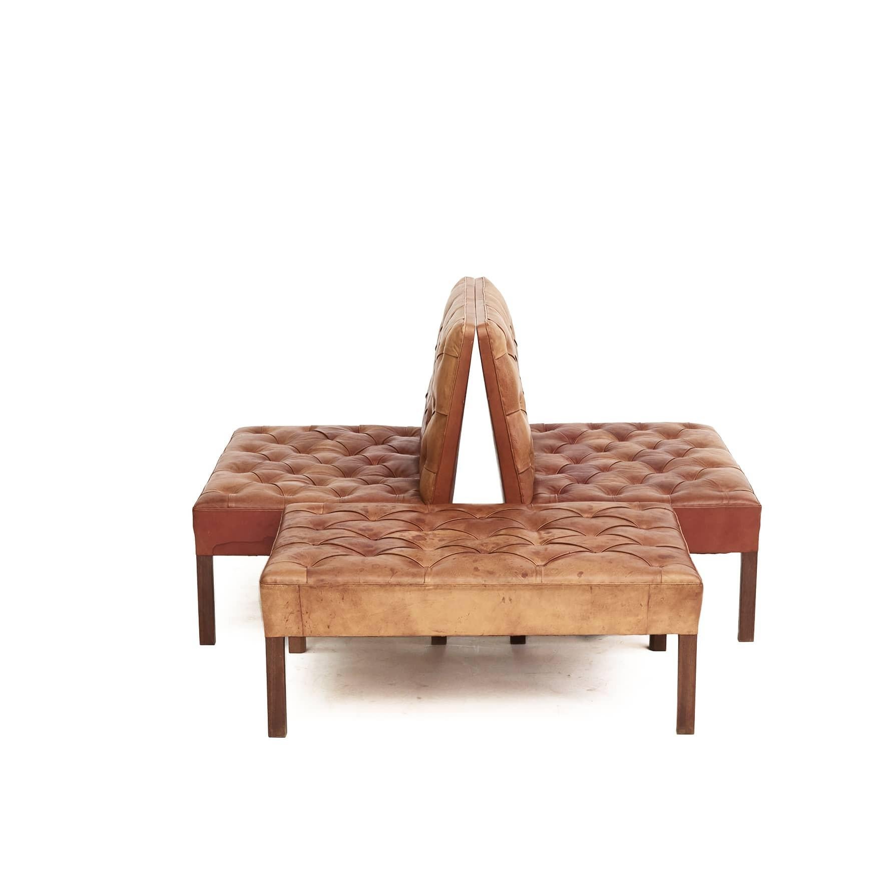 Kaare Klint 1888 - 1954.
A pair of addition sofas with mahogany legs and a low bench/stool.
Deep stitched seats, sides and back.
Upholstered with Niger leather, mahogany legs.

Made at Rud. Rasmussen's carpentry 1940 - 1950, which appears on the