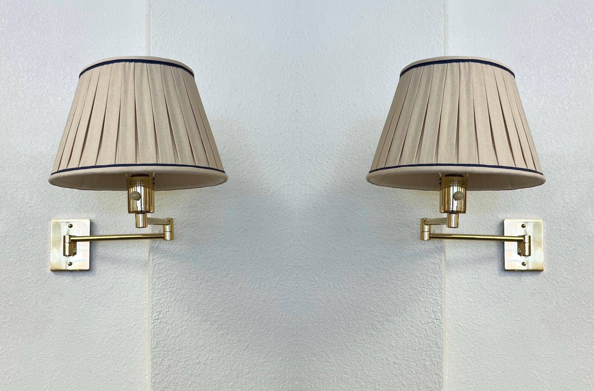 1970’s Pair of adjustable polish brass and linen wall sconces designed by George W. Hansen for Hanse Lamps NY. 

In beautiful vintage condition, shows minor wear consistent with age. 
Original lamp shades constructed of natural linen with a purple
