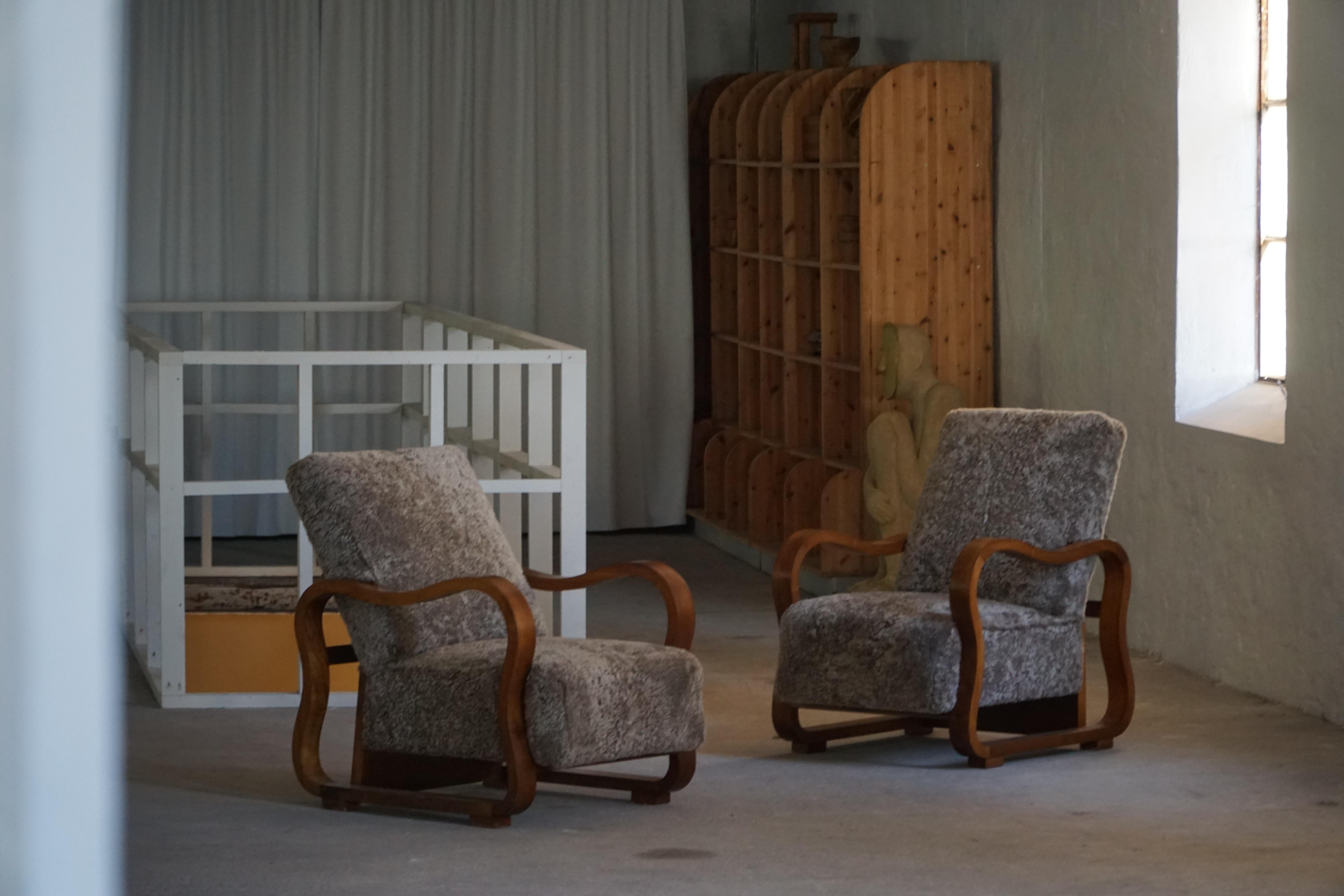 Este hermoso par de sillones daneses Art Decó de los años 30 ofrece una refinada mezcla de carpintería escultural y comodidad táctil. Los armazones están fabricados en nogal de tono cálido, lo que confiere a las sillas una presencia rica y acogedora