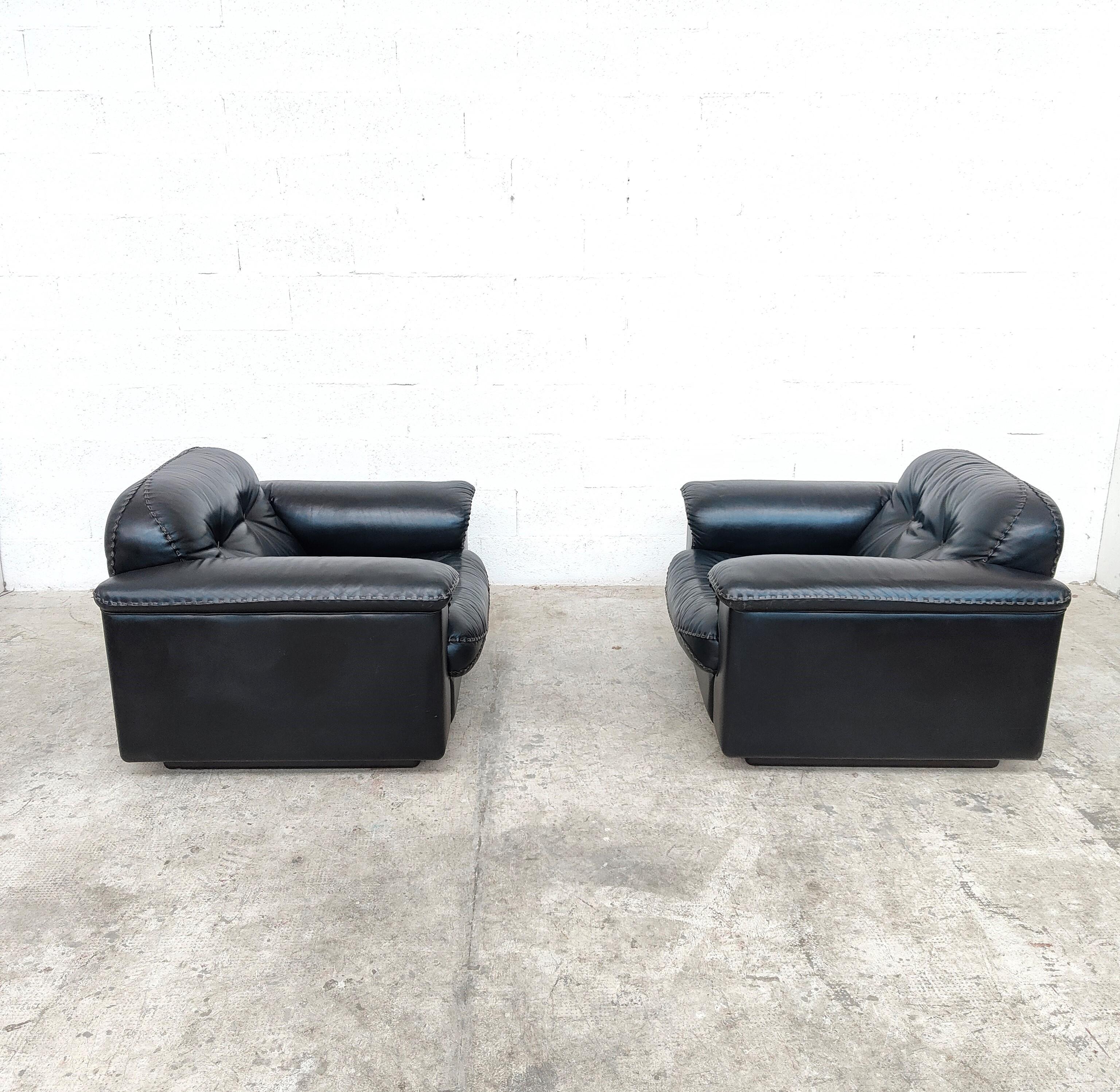 A pair of De Sede leather lounge chairs upholstered in dark black leather, c.1970s. These Swiss made chairs feature a reclining mechanism that allows the seats to extend forward while the back rests recline for maximum comfort. The hand stitched