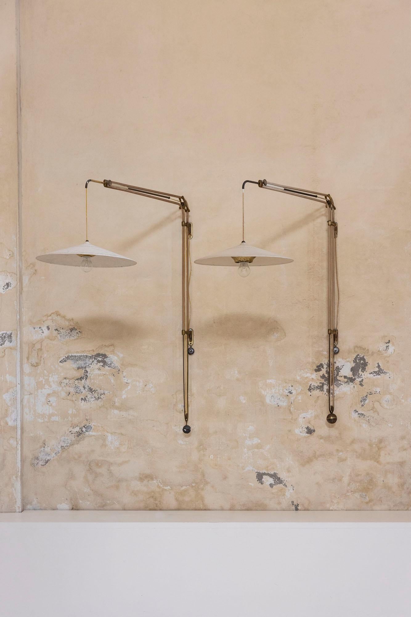 Rare paire d'appliques extensibles et ajustables, modèle B3, conçues par Franco Buzzi pour Oluce. Dotée d'une élégante structure en laiton et métal, chaque lampe est équipée d'un large abat-jour en aluminium laqué qui permet une diffusion large et