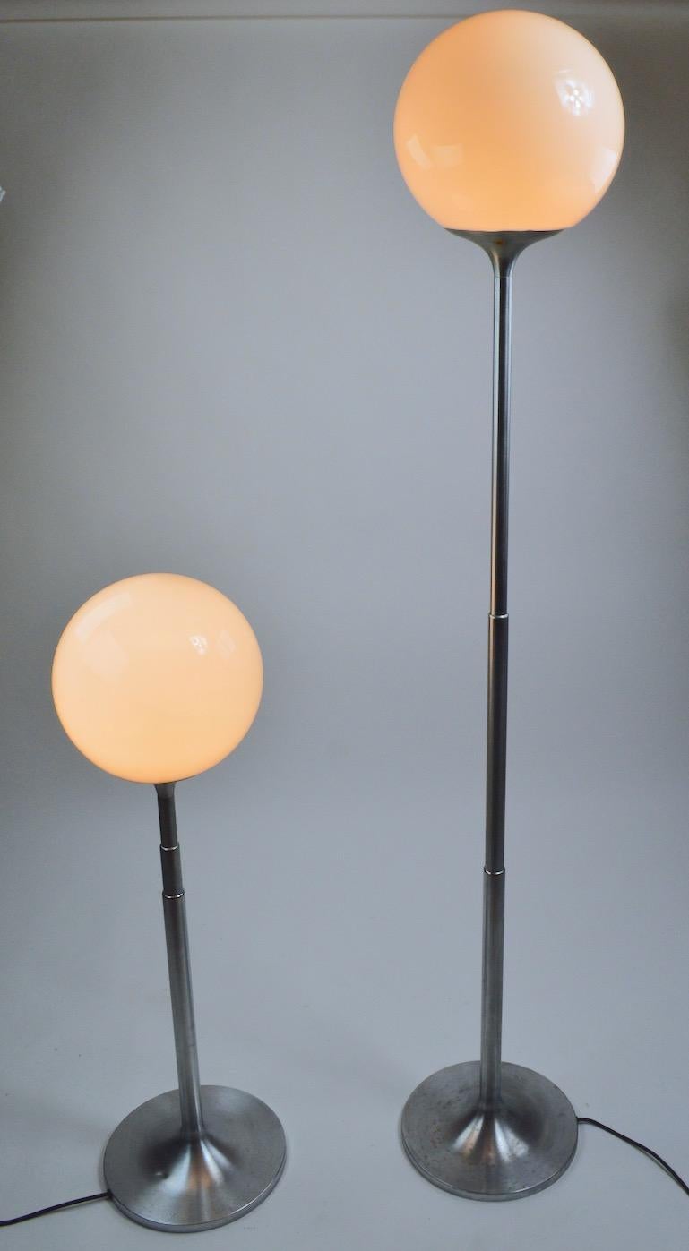 Rare and unusual pair of telescoping brushed steel floor lamps with glass ball globe tops. The lamps each have three concentric tubular tubes which can be extended or condensed to adjust the height. Lamps in totally extended position 70 inch H x