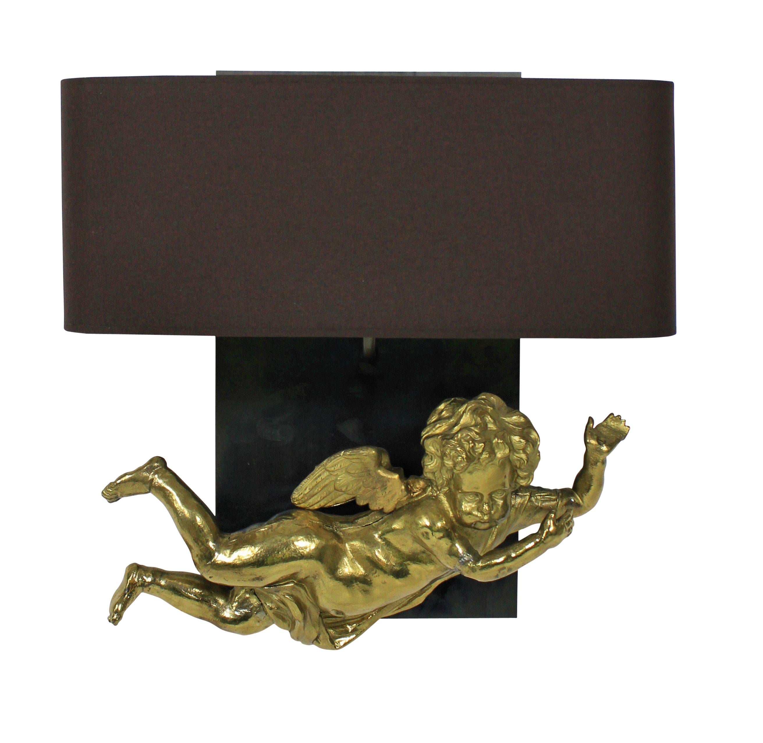 A pair of unusual French wall sconces incorporating two early 19th century gilt metal cherubs on polished steel back plates with half shades.