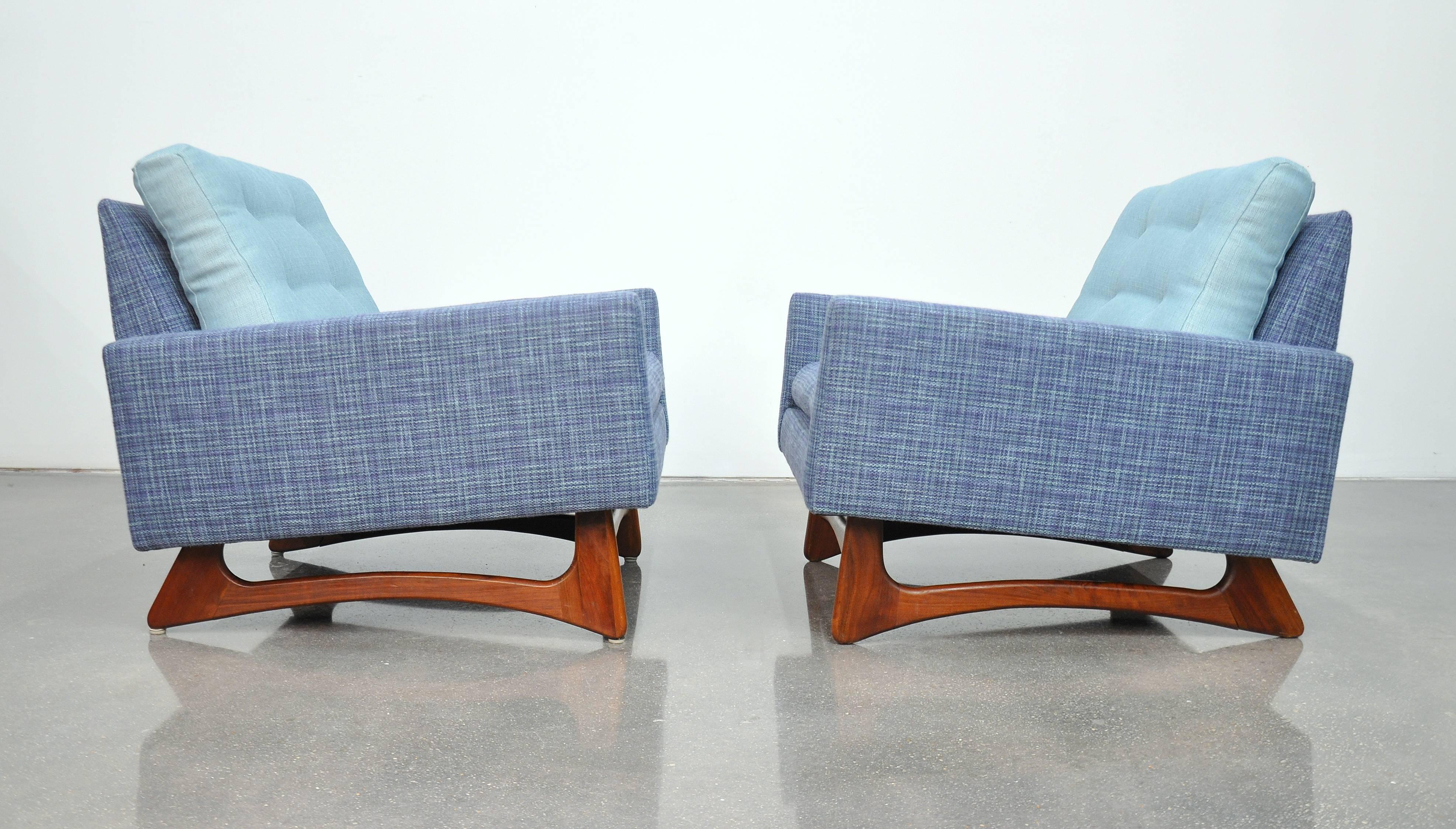 A pair of newly reupholstered Mid-Century Modern model 2406-C tufted club chairs featuring a beautifully grained, sculpted walnut frame, a quintessential characteristic of designer Adrian Pearsall. Each vintage armchair has been recovered in navy or