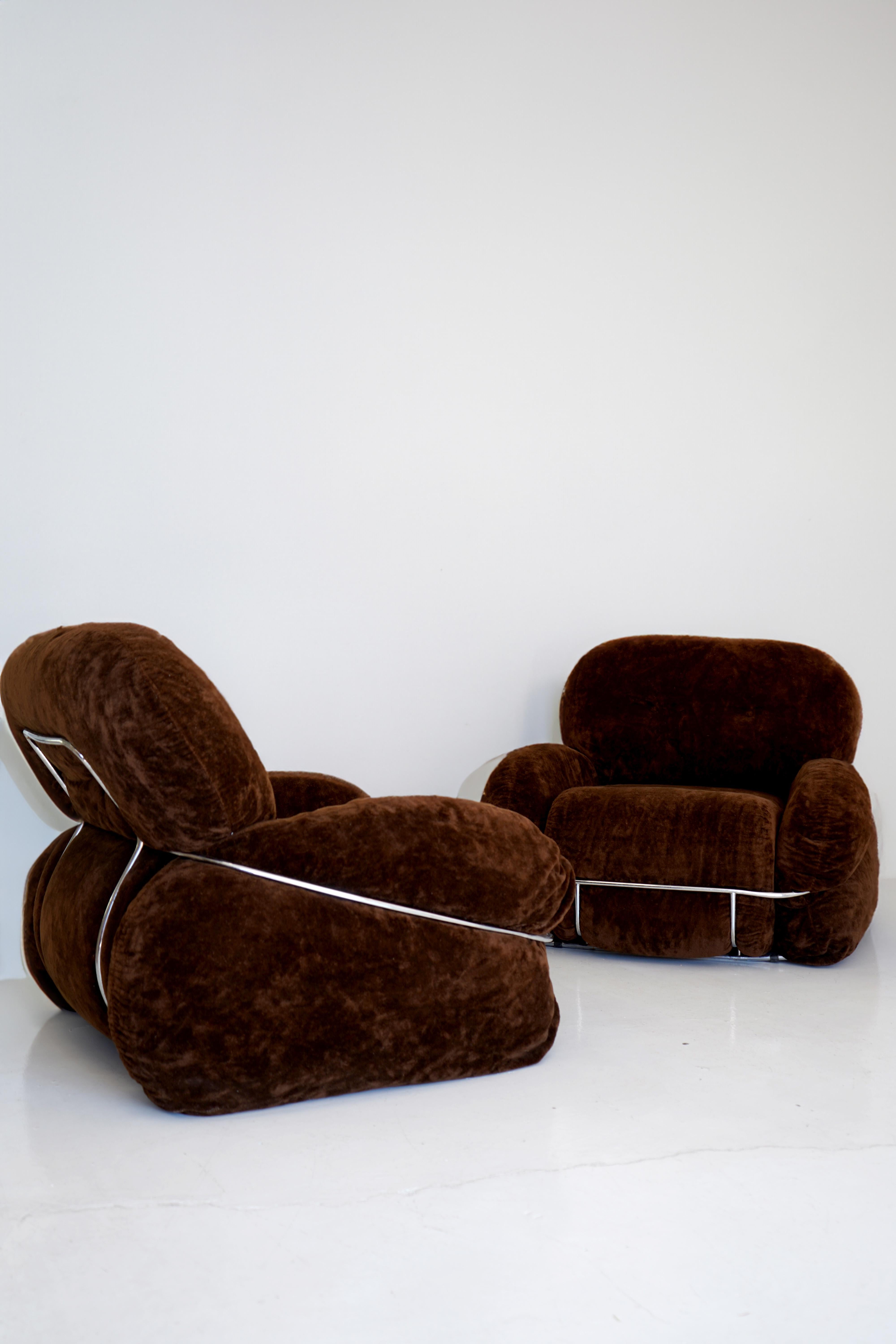 Pair of Okay lounge chairs by Adriano Piazzesi. Exaggerated curves wrapping in and out of a looping chrome frame. Original chocolate brown velvet remains in good vintage condition with no tears or stains. Priced as a pair.